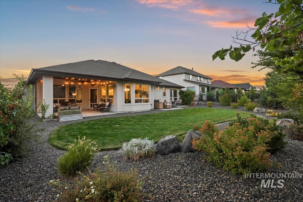 Rear view of house with a patio area, a yard, stucco siding, and a shingled roof