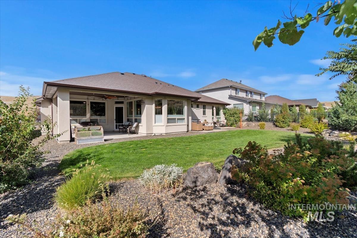 Back of house featuring a patio, a ceiling fan, stucco siding, and a lawn