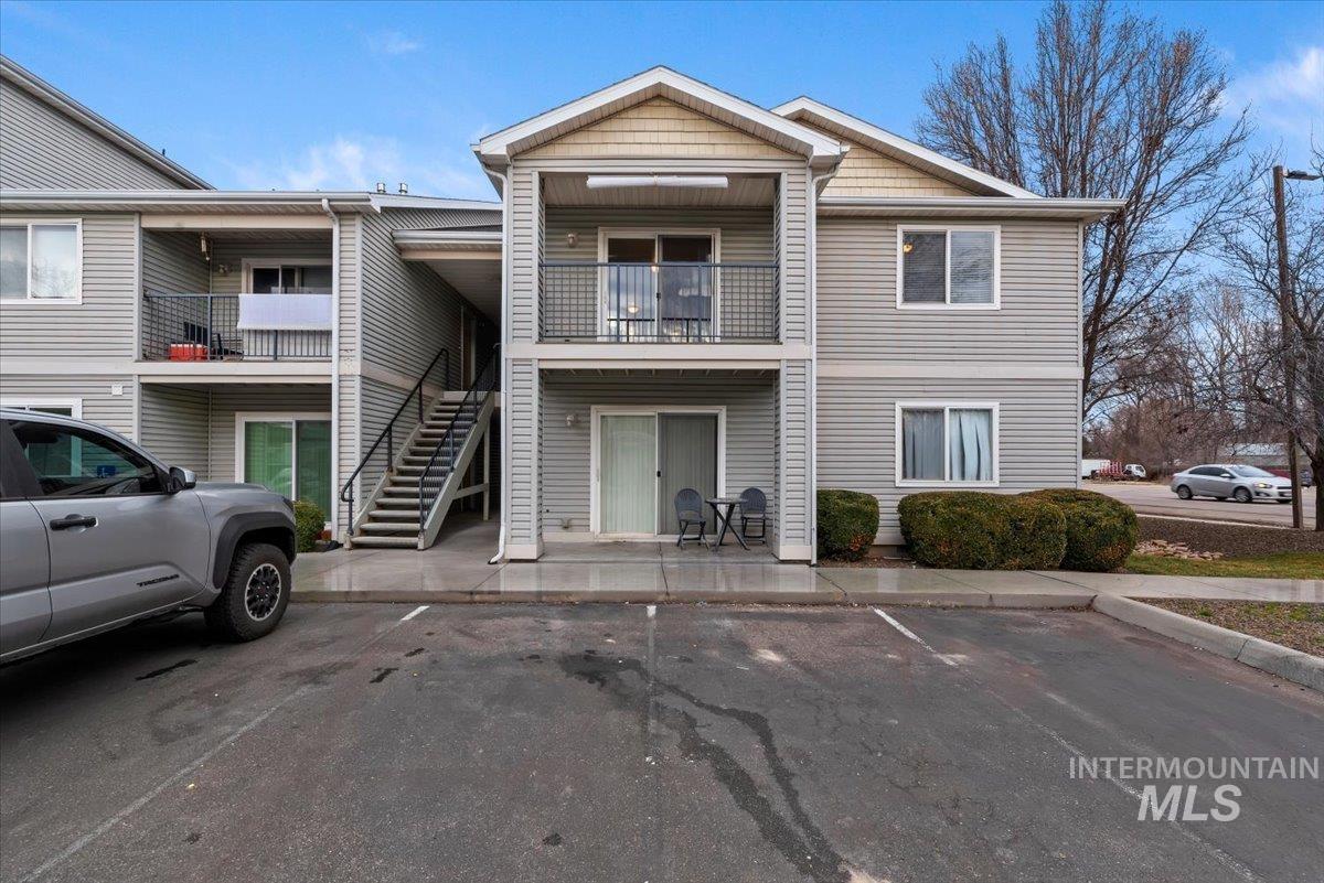 View of property with stairs and uncovered parking