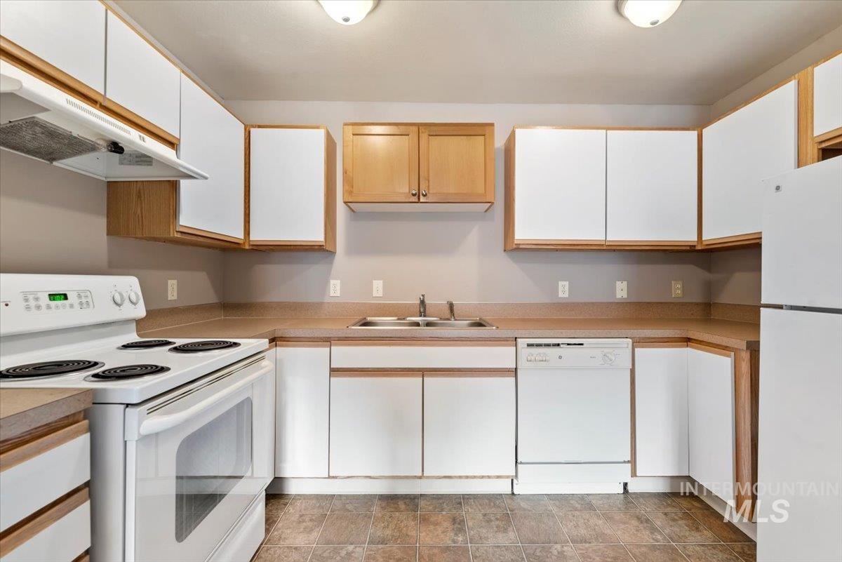 Kitchen featuring white appliances, light countertops, and dual tone cabinetry