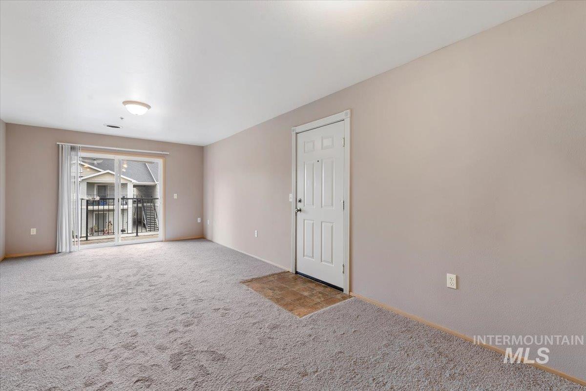 Carpeted spare room featuring baseboards