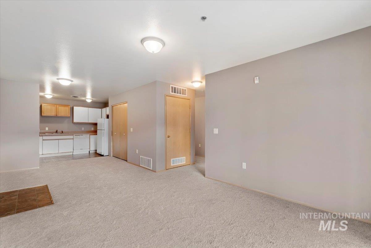 Unfurnished living room featuring light carpet and a sink