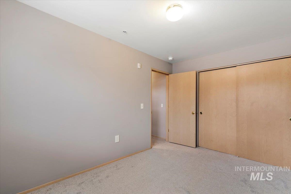 Unfurnished bedroom featuring light carpet and a closet