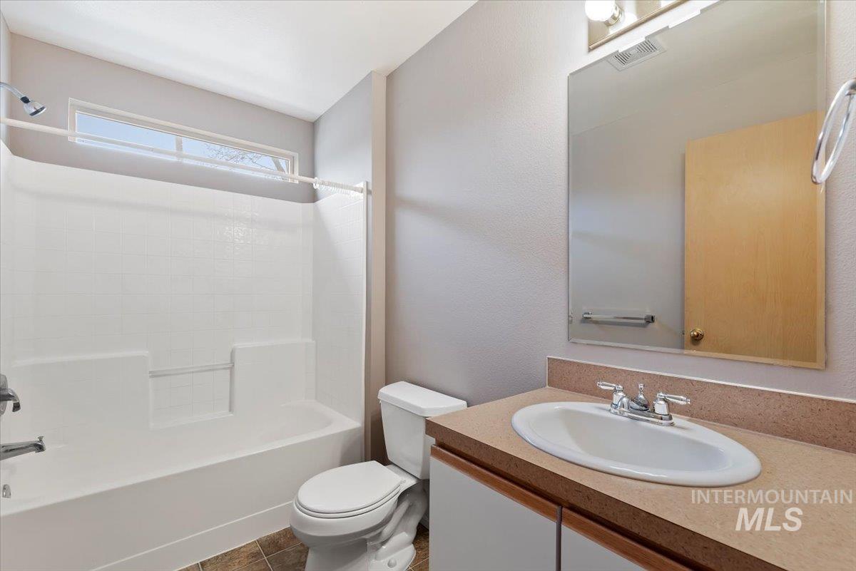 Bathroom featuring vanity, washtub / shower combination, and a textured wall