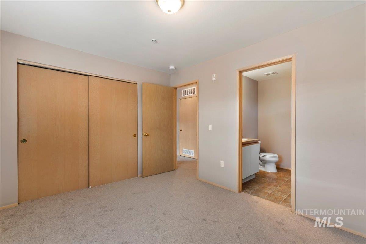 Unfurnished bedroom with light colored carpet, a closet, and connected bathroom