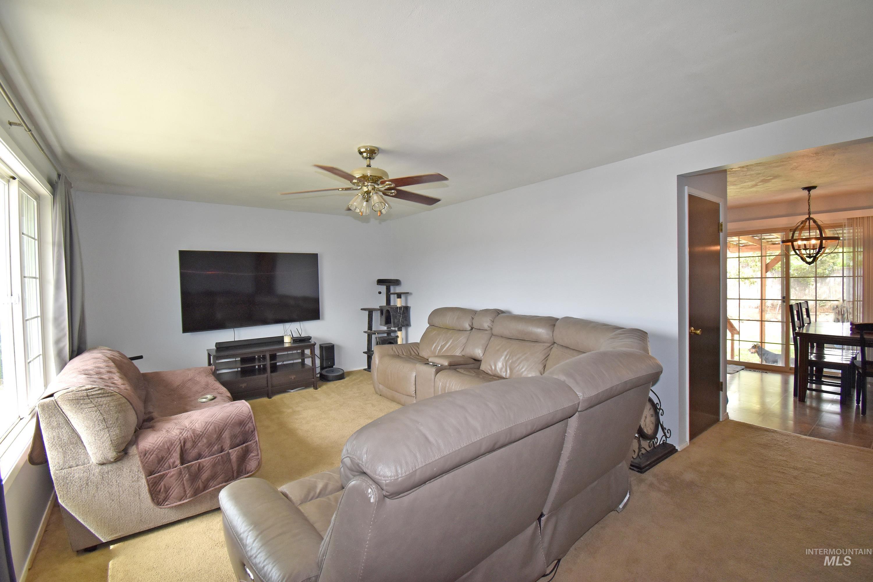 Carpeted living area with a chandelier and a ceiling fan