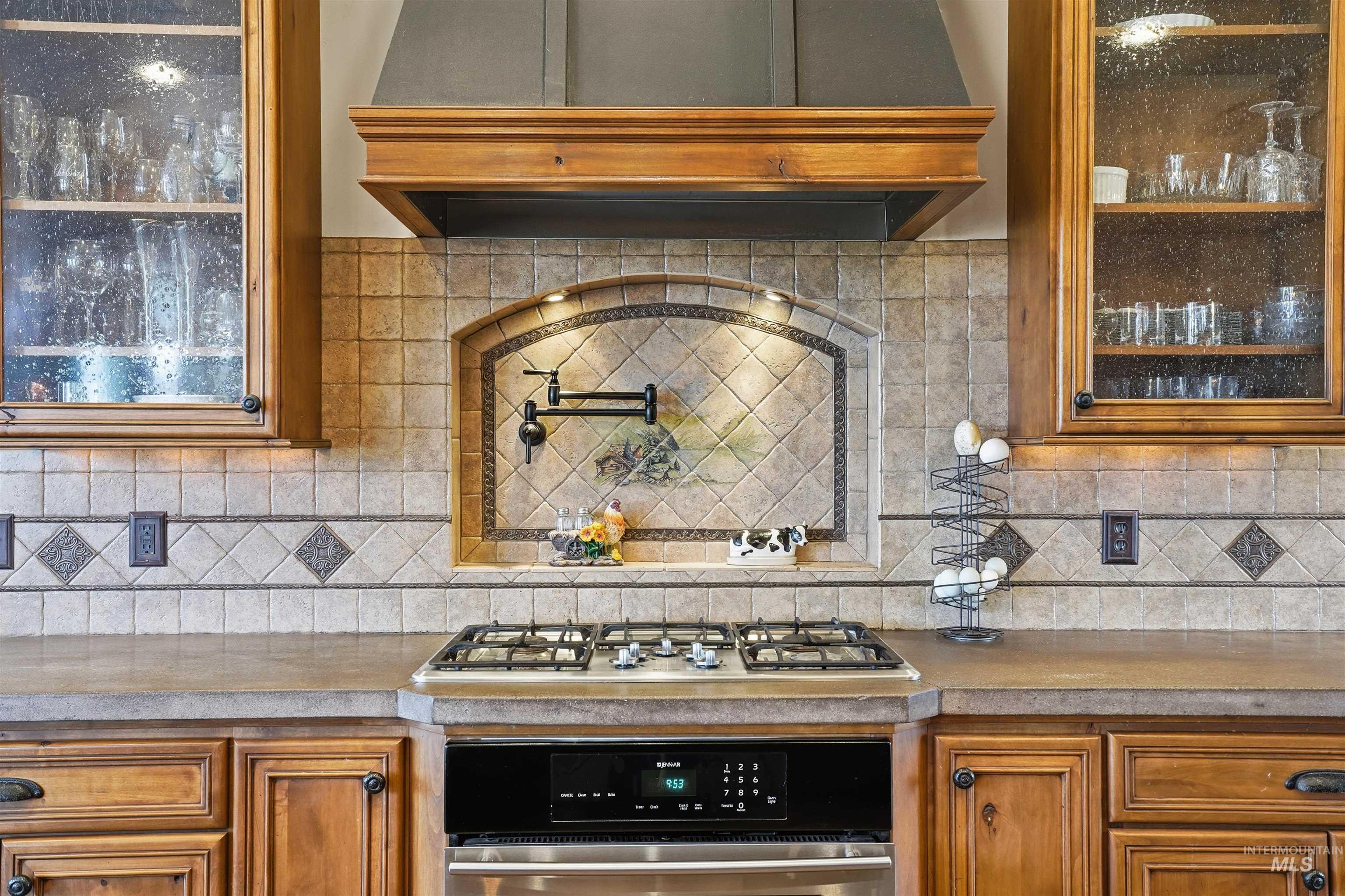 Kitchen with extractor fan, glass fronted cabinets, wood finish cabinetry, and light countertops