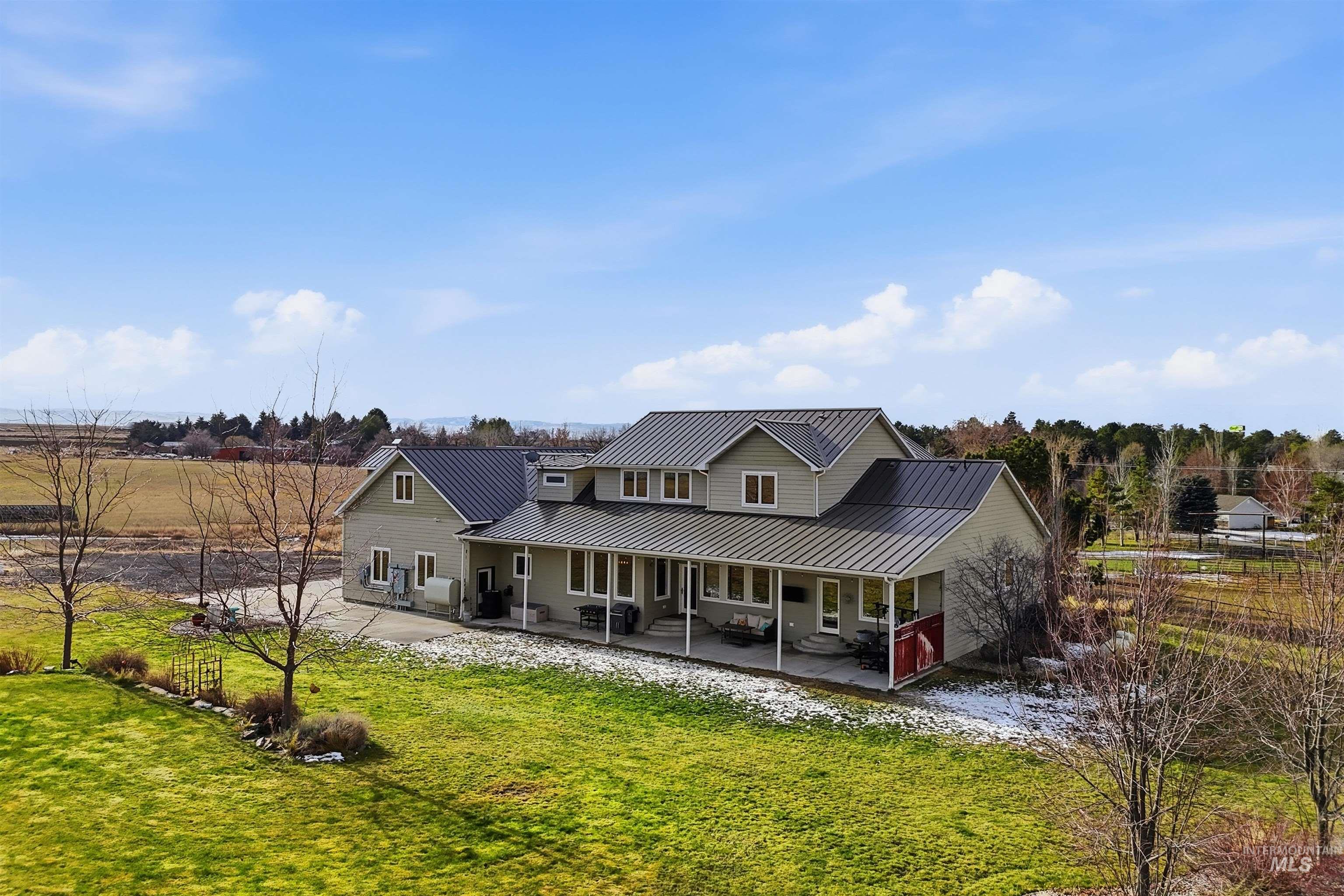 Back of property with a standing seam roof, a patio, and a lawn