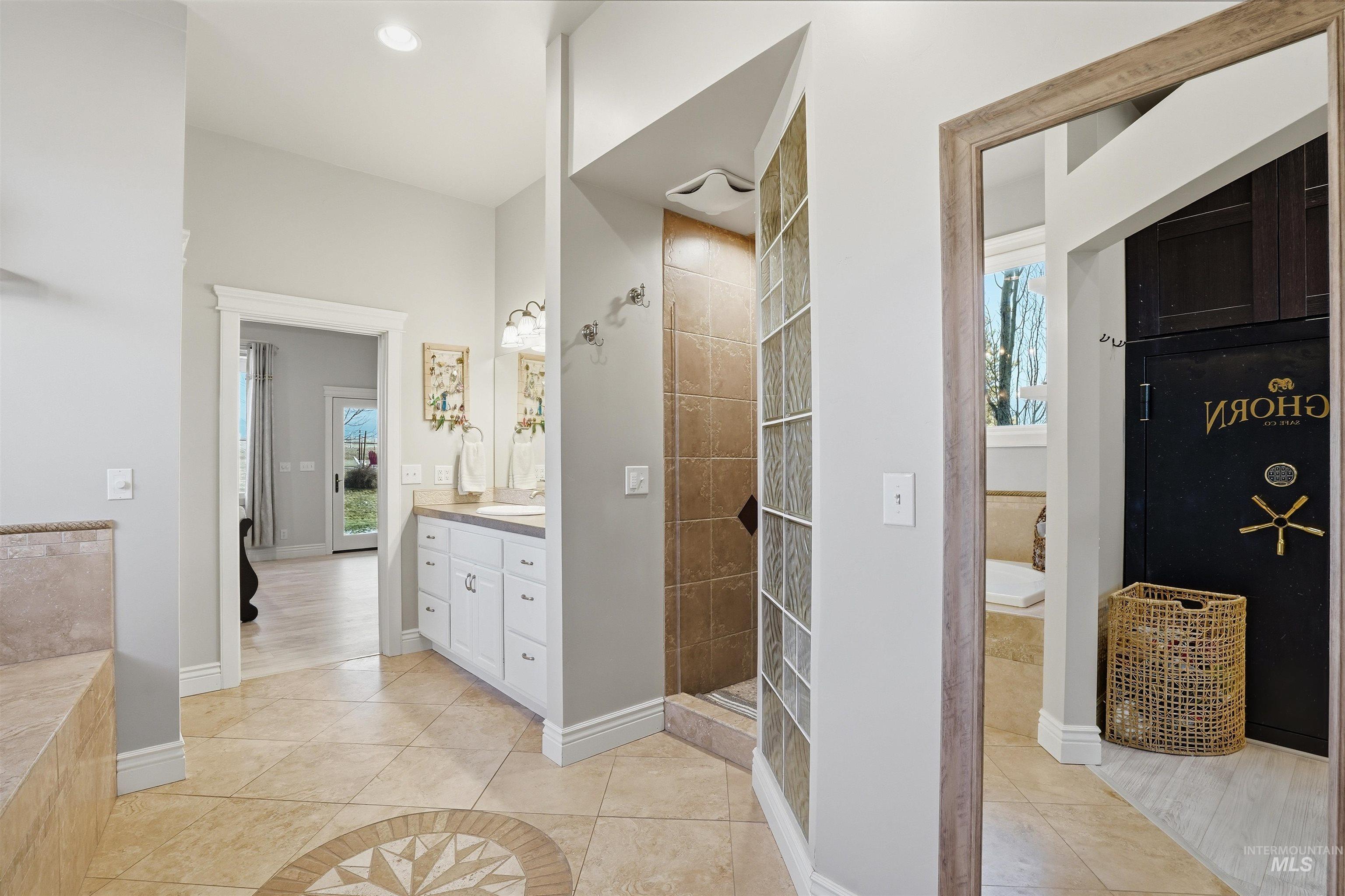 Full bath with light tile patterned floors, a garden tub, a walk in shower, and vanity