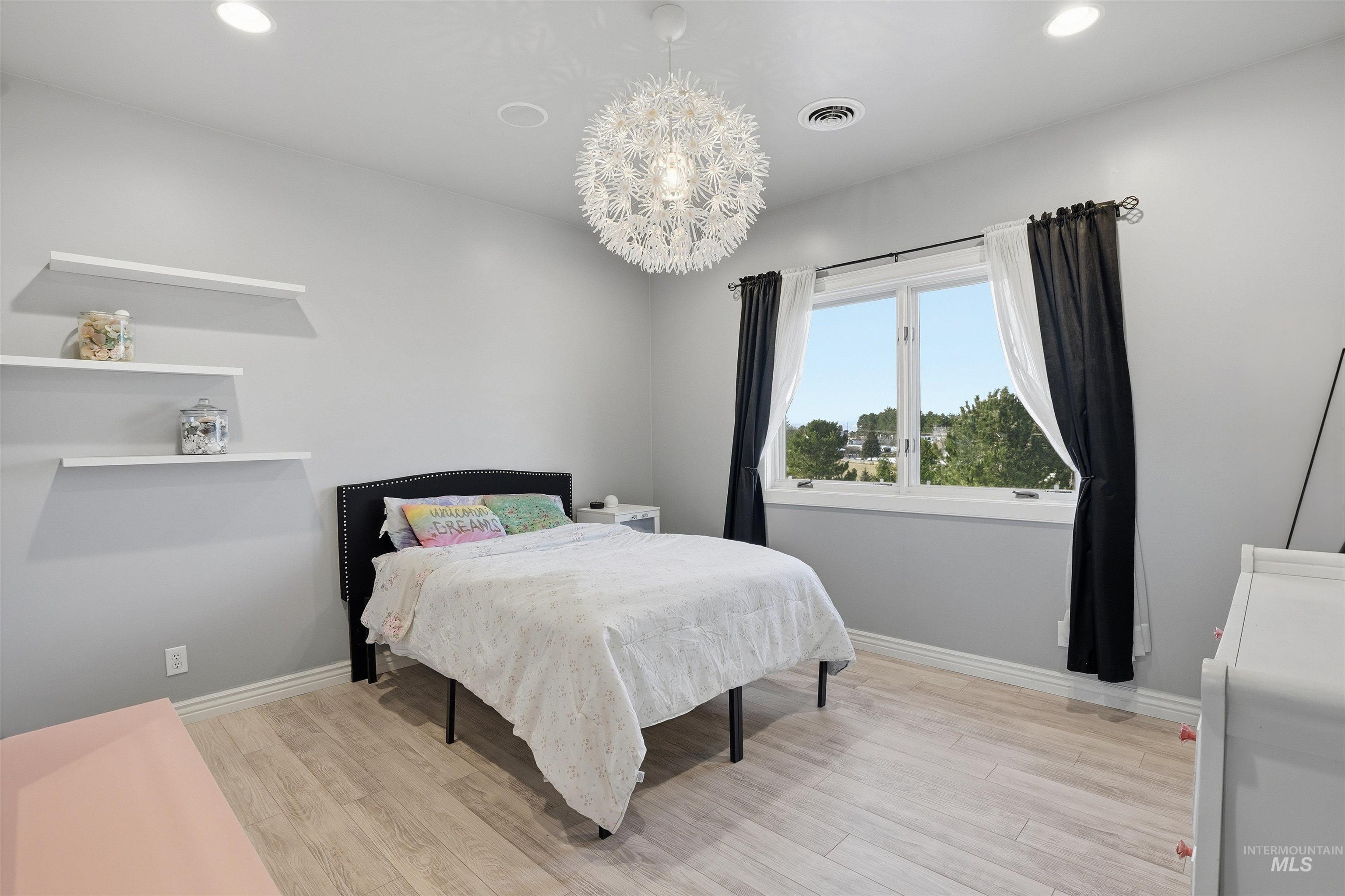 Bedroom with light wood finished floors and a chandelier
