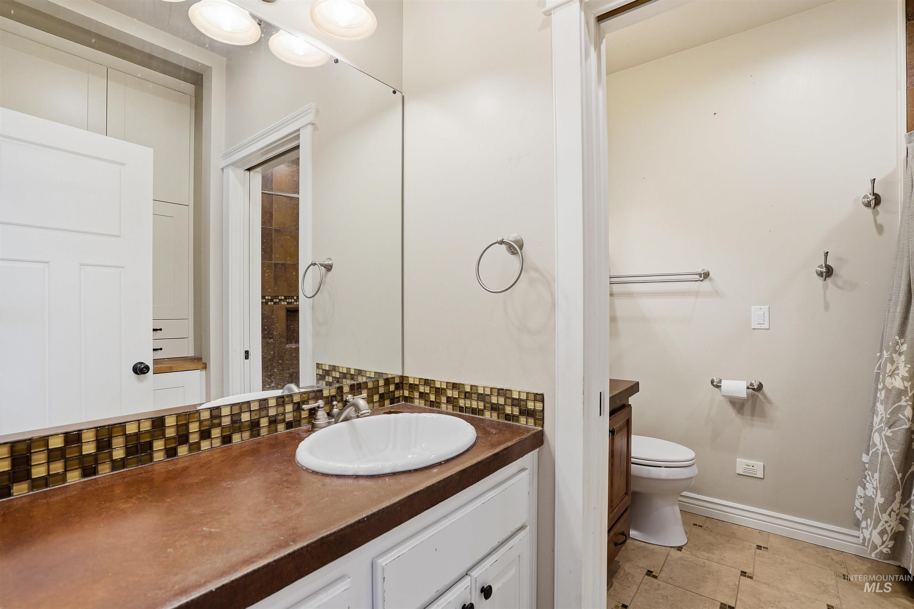 Full bathroom with vanity, decorative backsplash, a shower with curtain, and light tile patterned floors