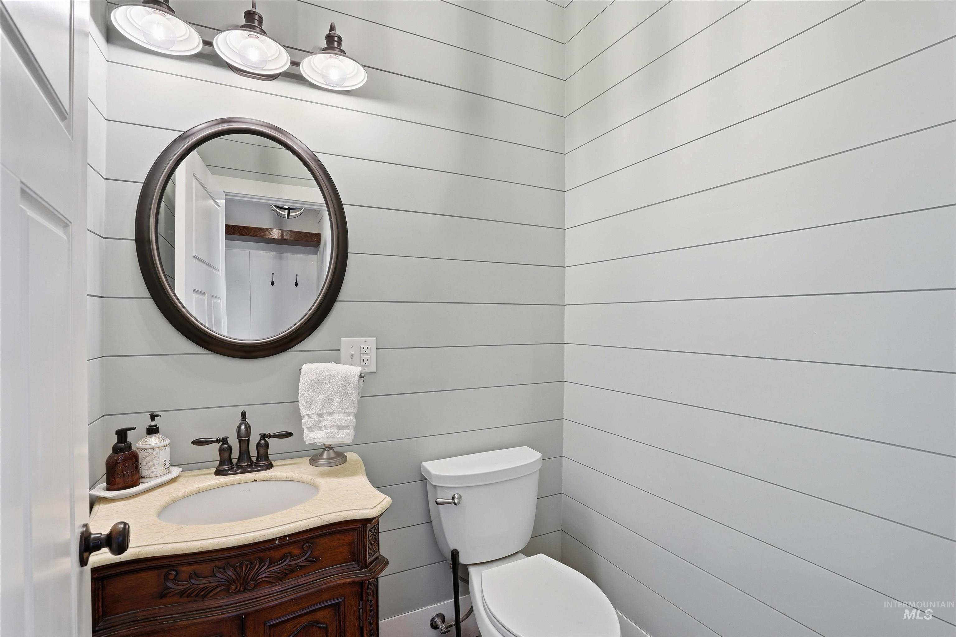 Half bath with vanity and wood walls