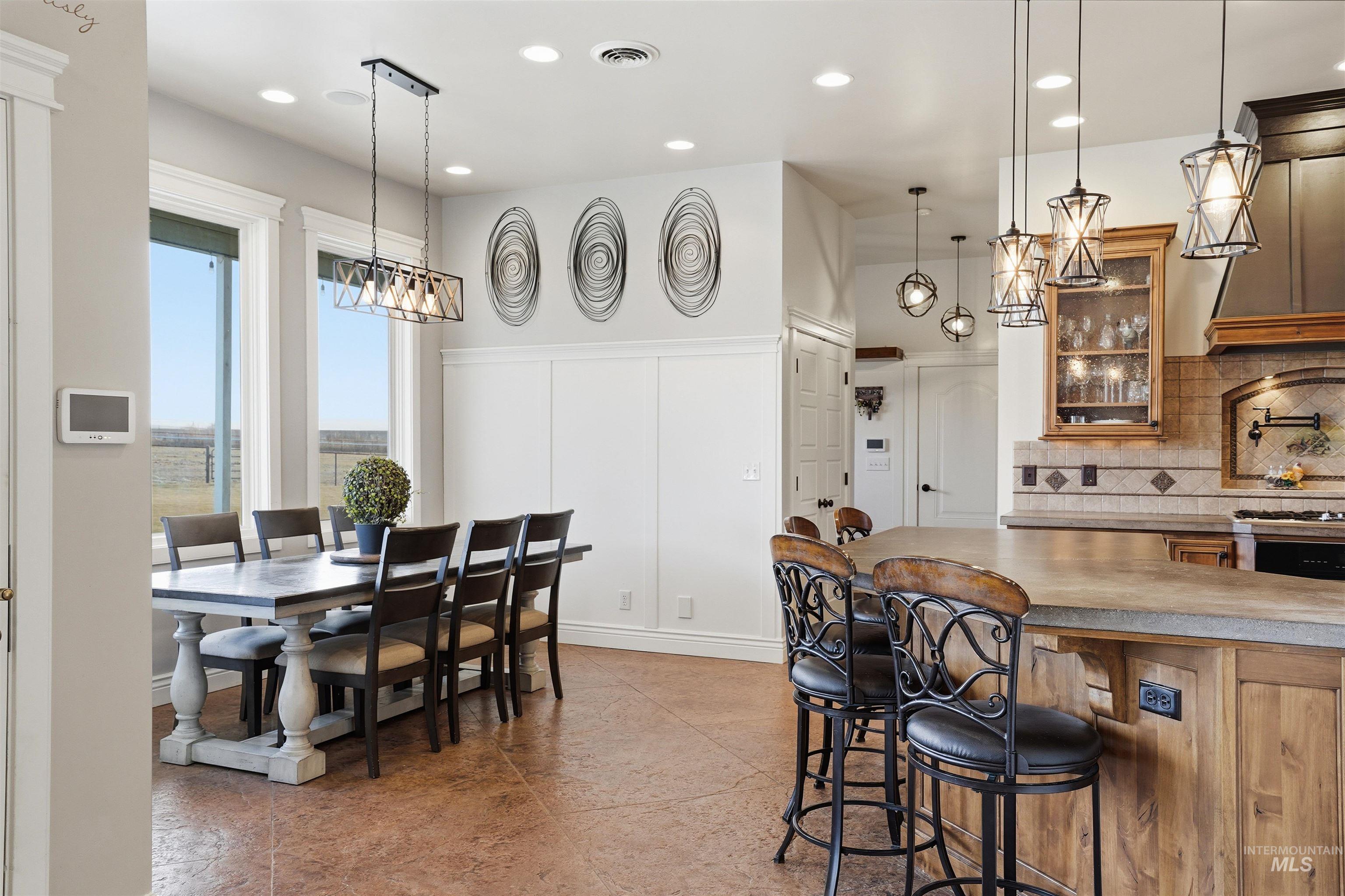 Kitchen with glass insert cabinets, wood finish cabinets, a breakfast bar, suspended lighting, and decorative backsplash