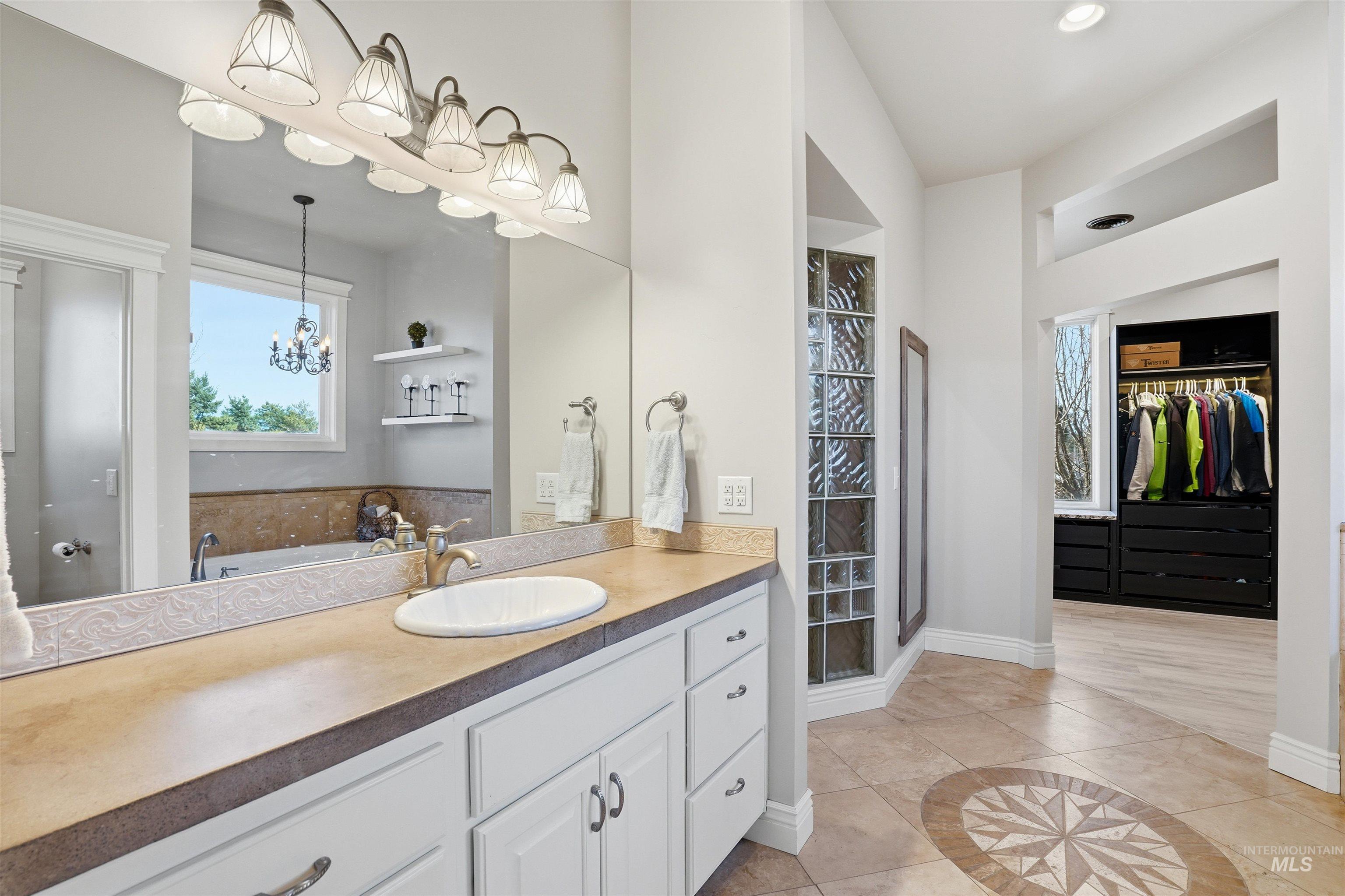 Bathroom featuring a spacious closet, inlaid floor details, vanity, light tile patterned floors, and a stall shower