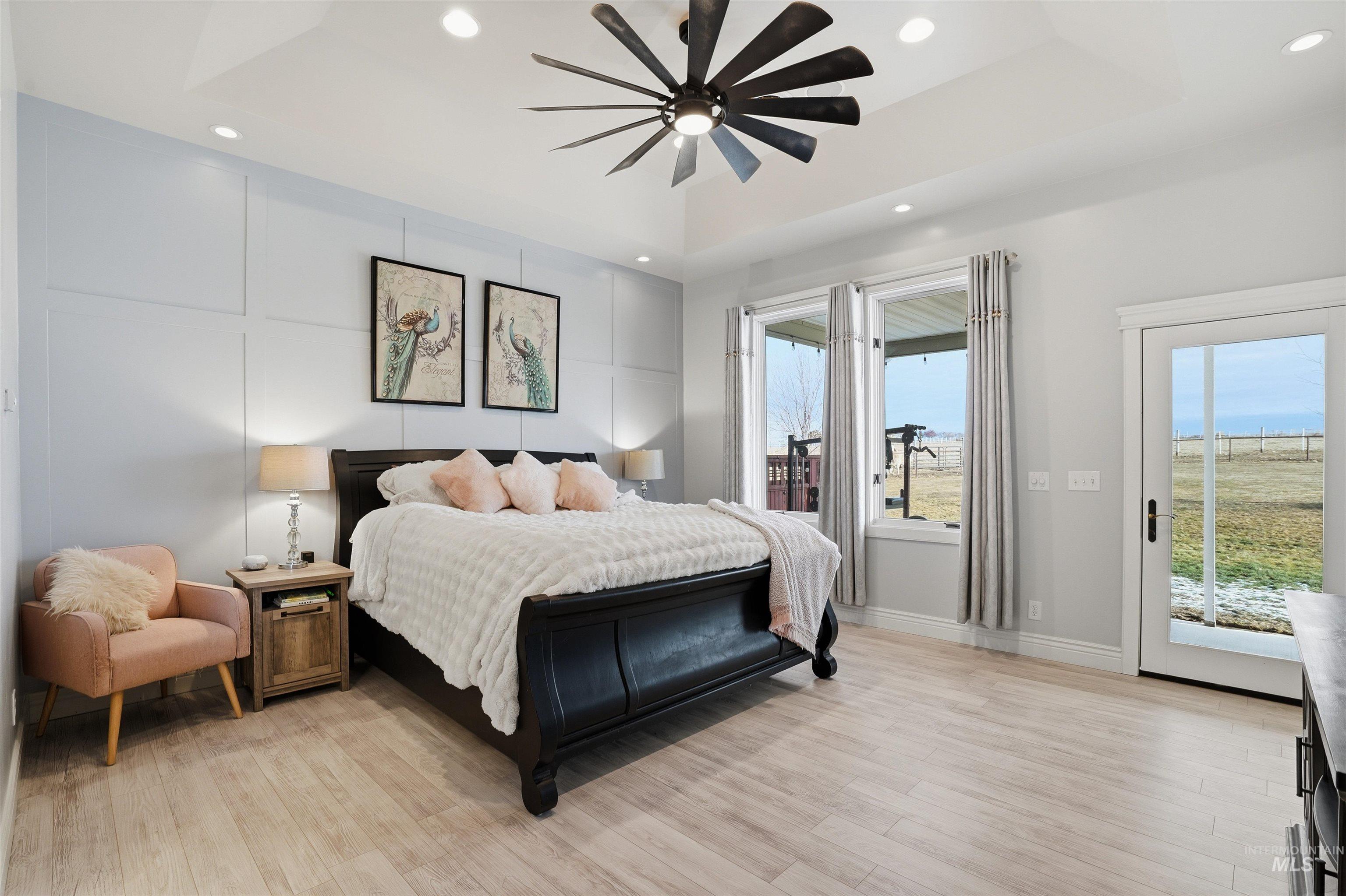 Bedroom with access to exterior, light wood-type flooring, recessed lighting, a ceiling fan, and a decorative wall