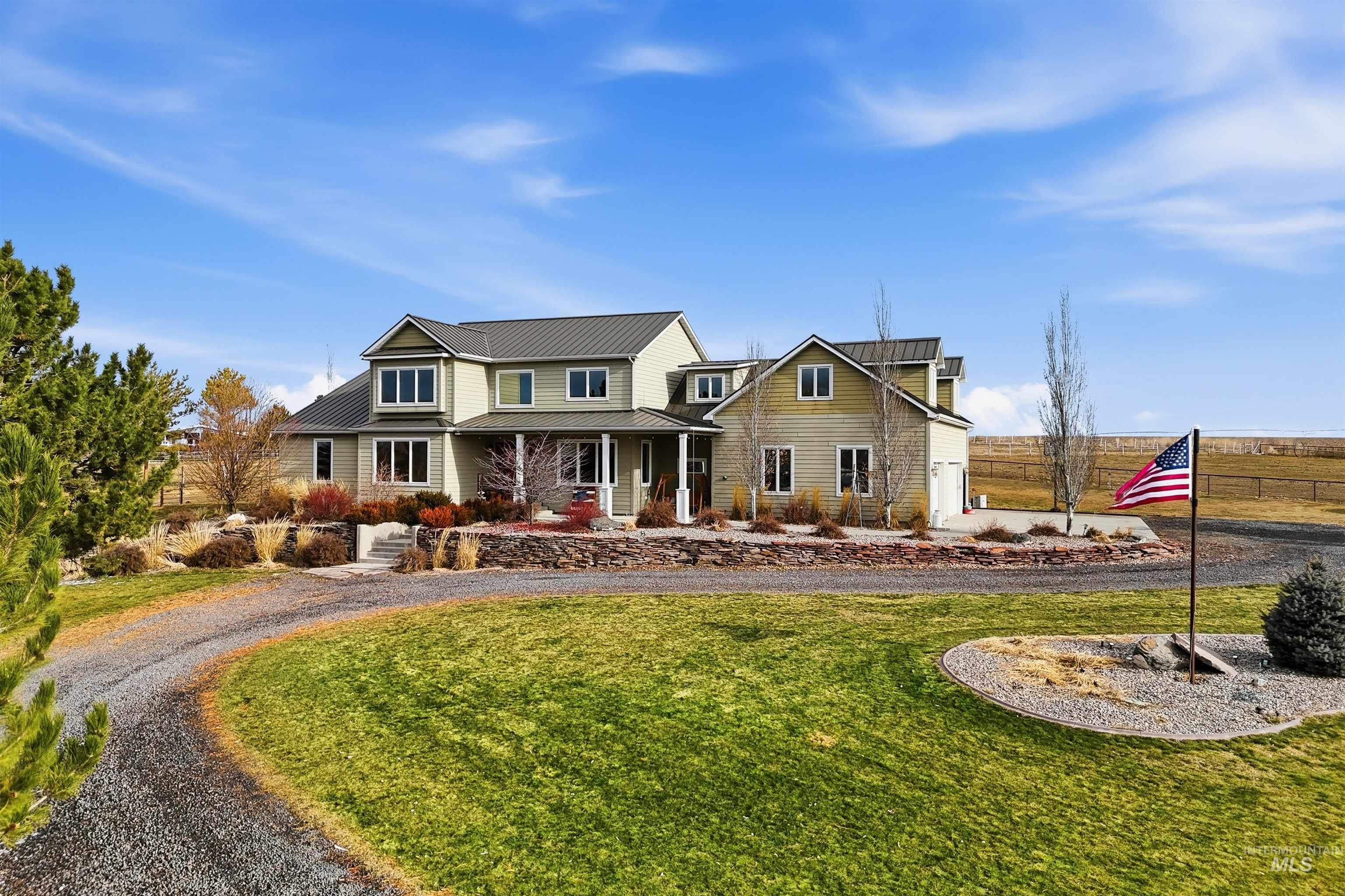 View of front of house featuring a porch, a standing seam roof, curved driveway, and a garage