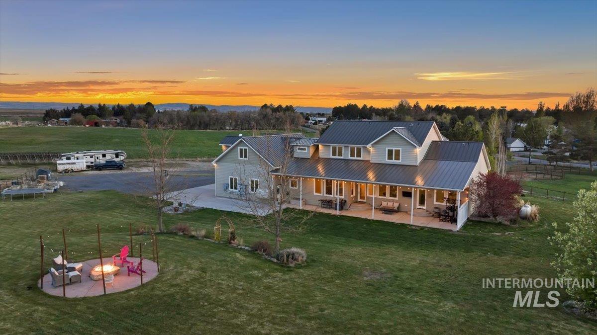 Back of property at dusk featuring a patio, a metal roof, a lawn, and a fire pit