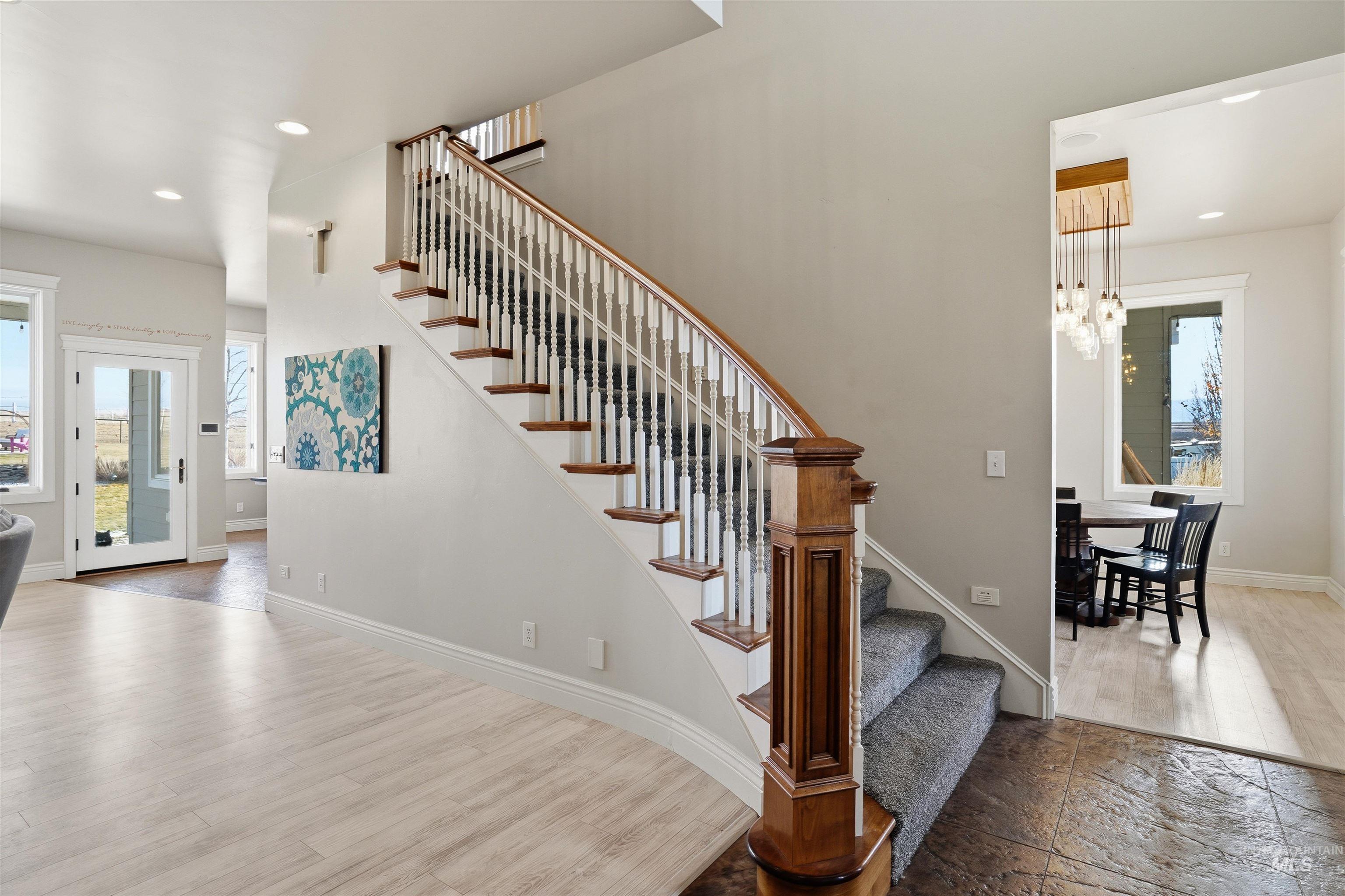 Stairway featuring plenty of natural light, suspended lighting, and wood finished floors