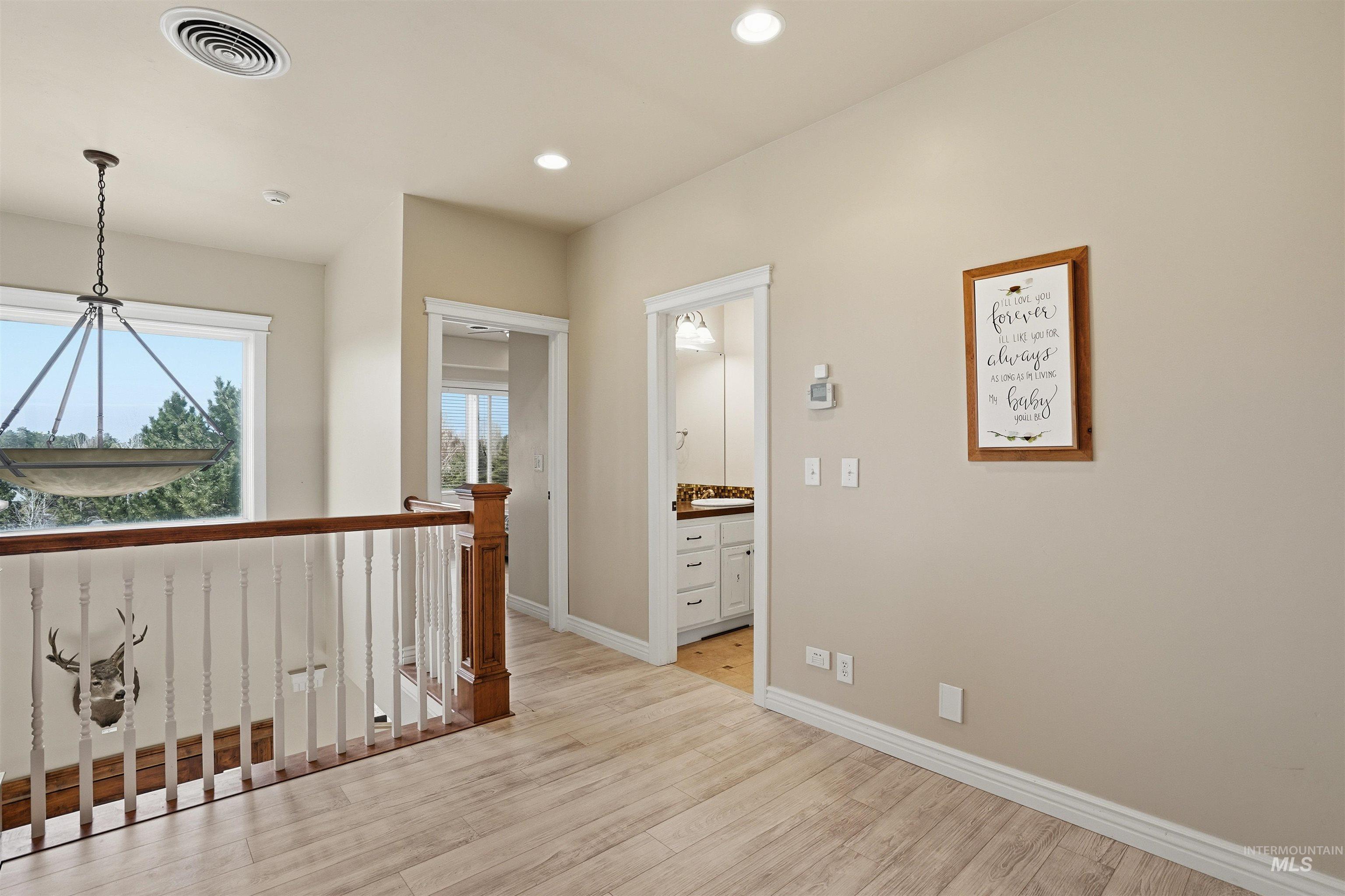 Hall with light wood-type flooring, an upstairs landing, and recessed lighting
