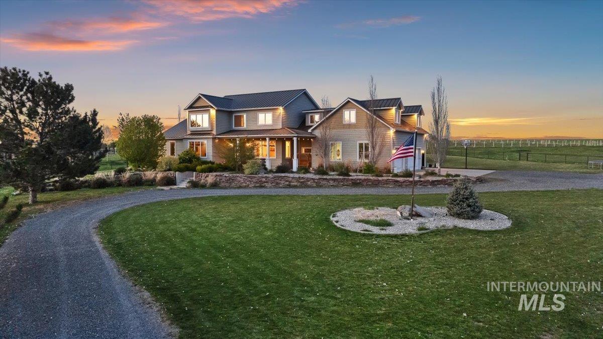 View of front of house featuring a porch, curved driveway, and a standing seam roof