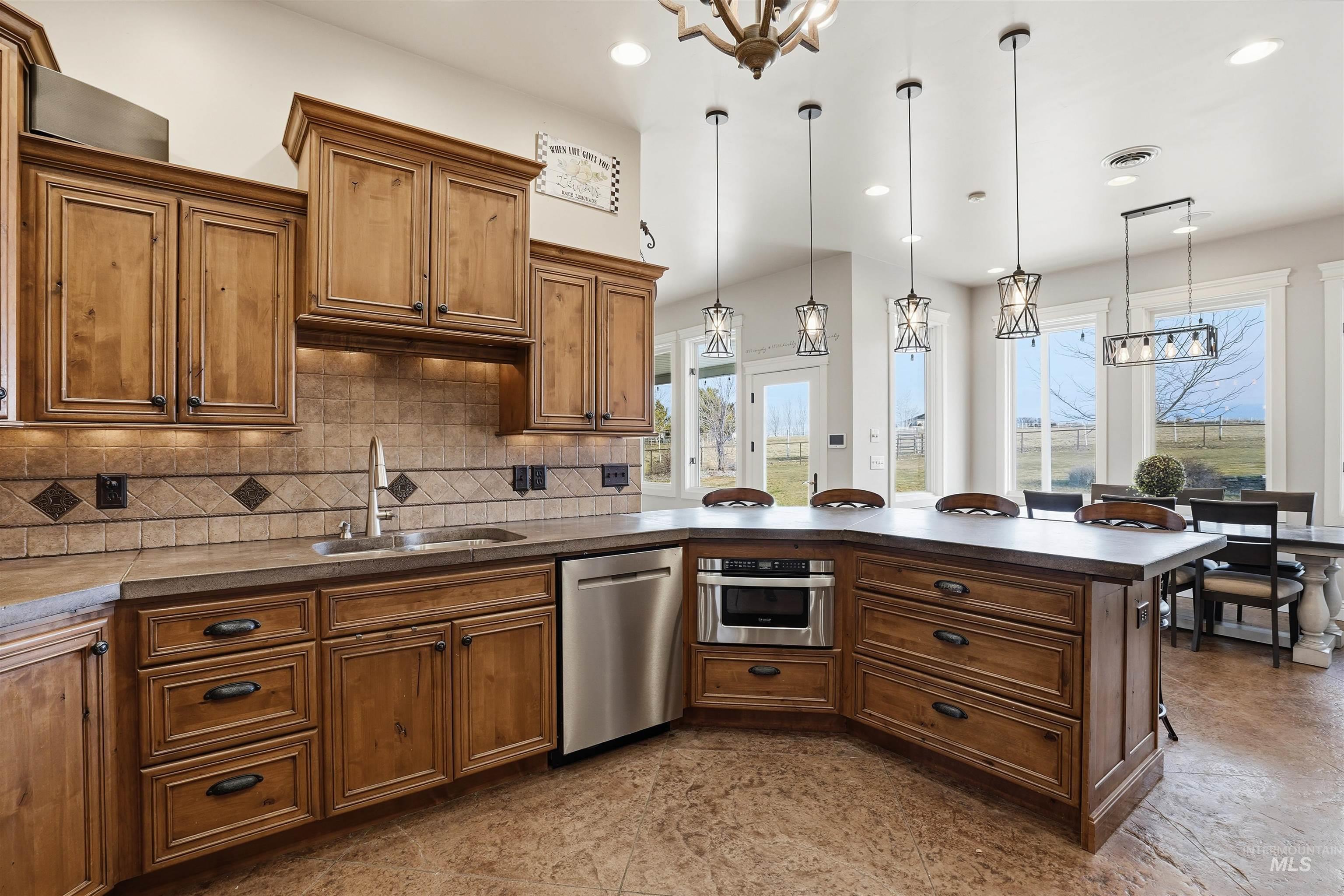 Kitchen featuring a chandelier, wood finish cabinetry, a peninsula, stainless steel appliances, and a kitchen breakfast bar