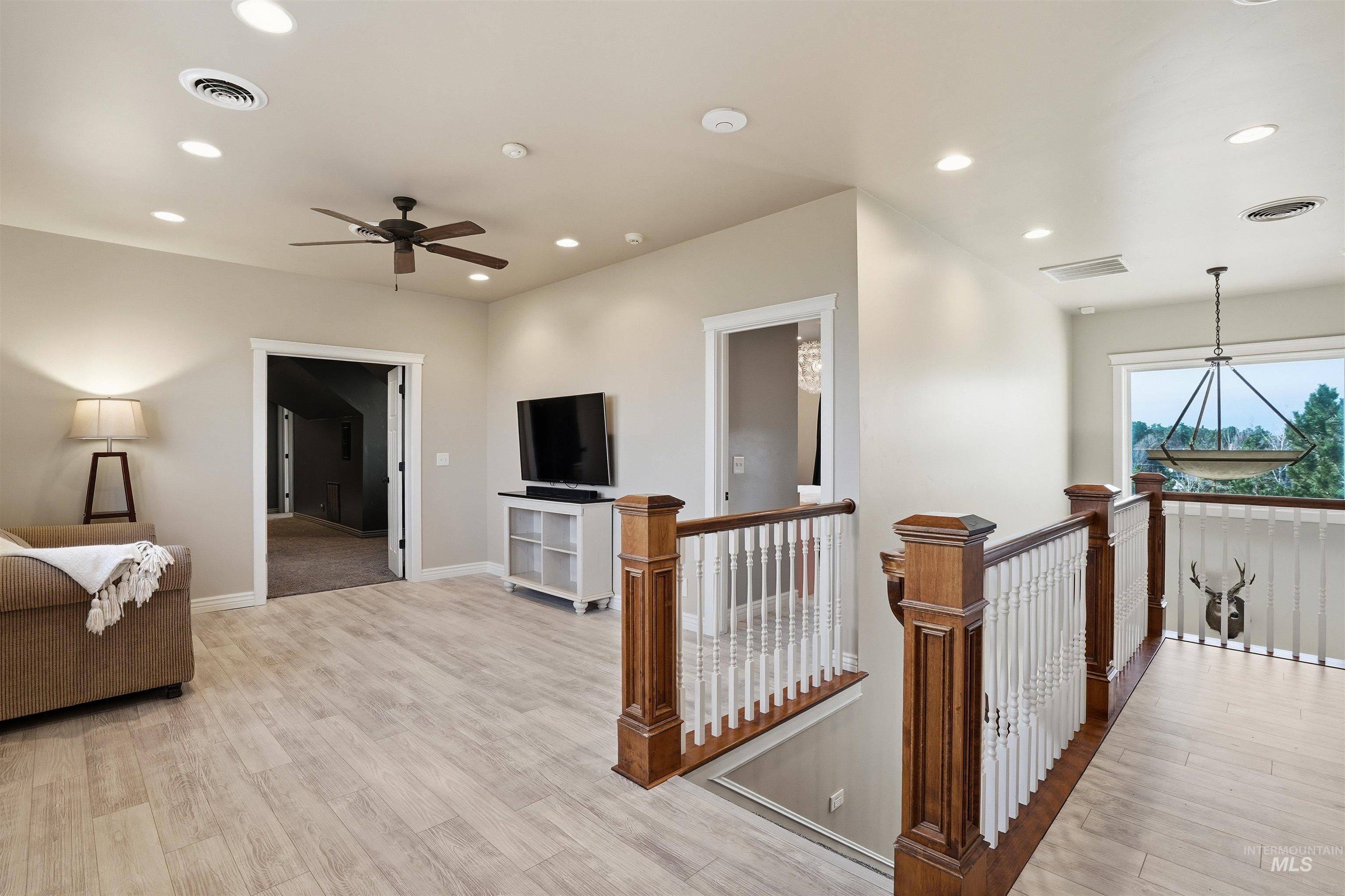 Corridor with light wood-type flooring, an upstairs landing, and recessed lighting