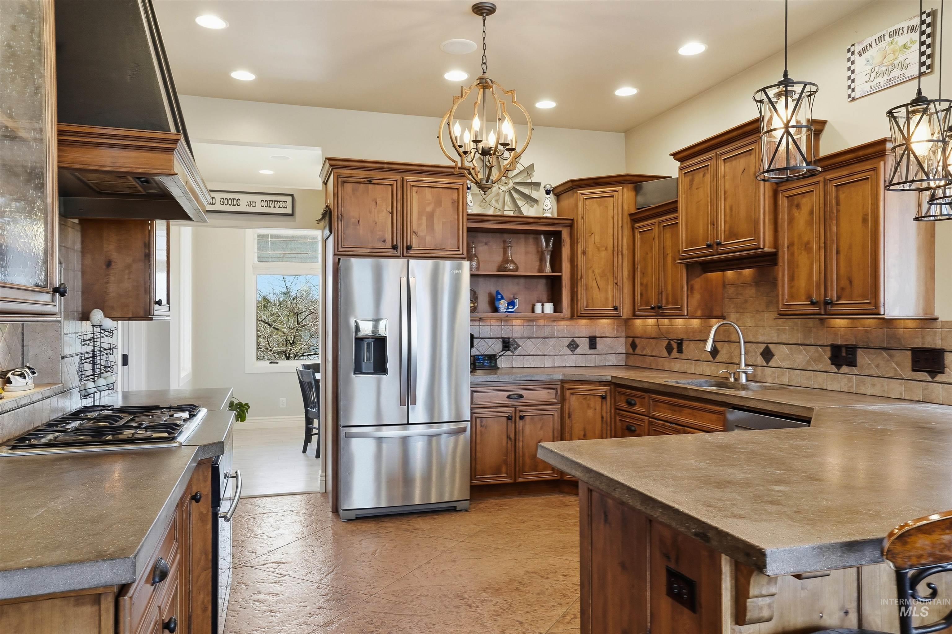 Kitchen with wood finish cabinets, decorative backsplash, stainless steel appliances, and a peninsula
