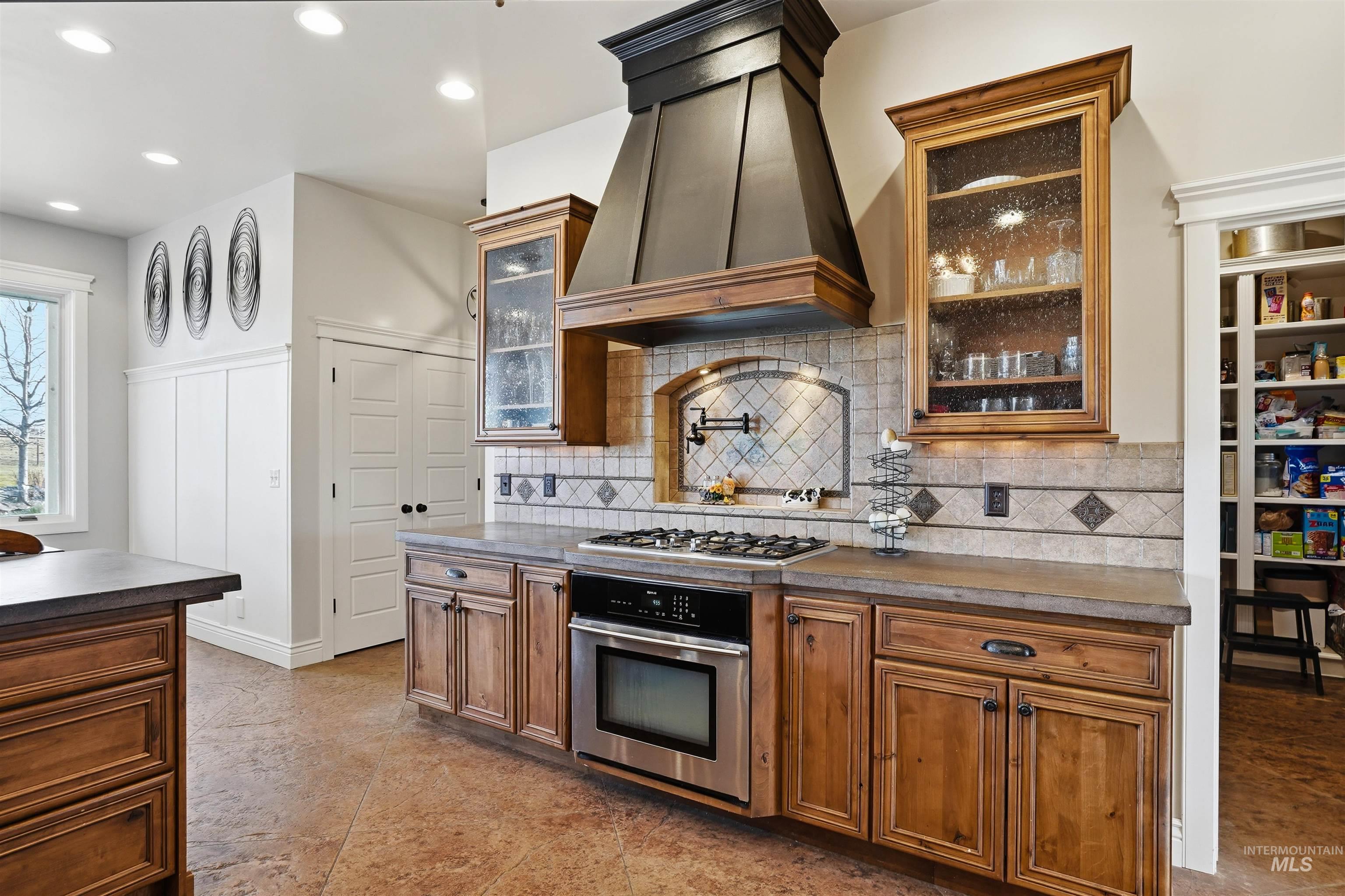 Kitchen with stainless steel appliances, wood finish cabinets, glass insert cabinets, recessed lighting, and decorative backsplash