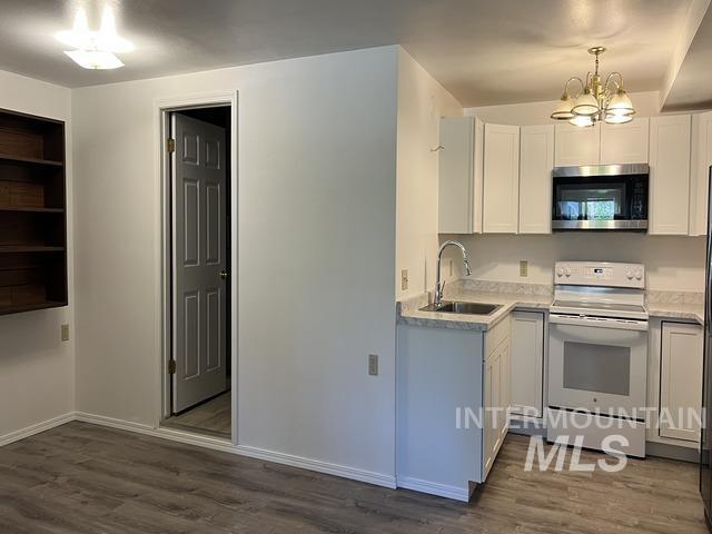 Kitchen featuring white electric stove, stainless steel microwave, a chandelier, and dark wood-style floors