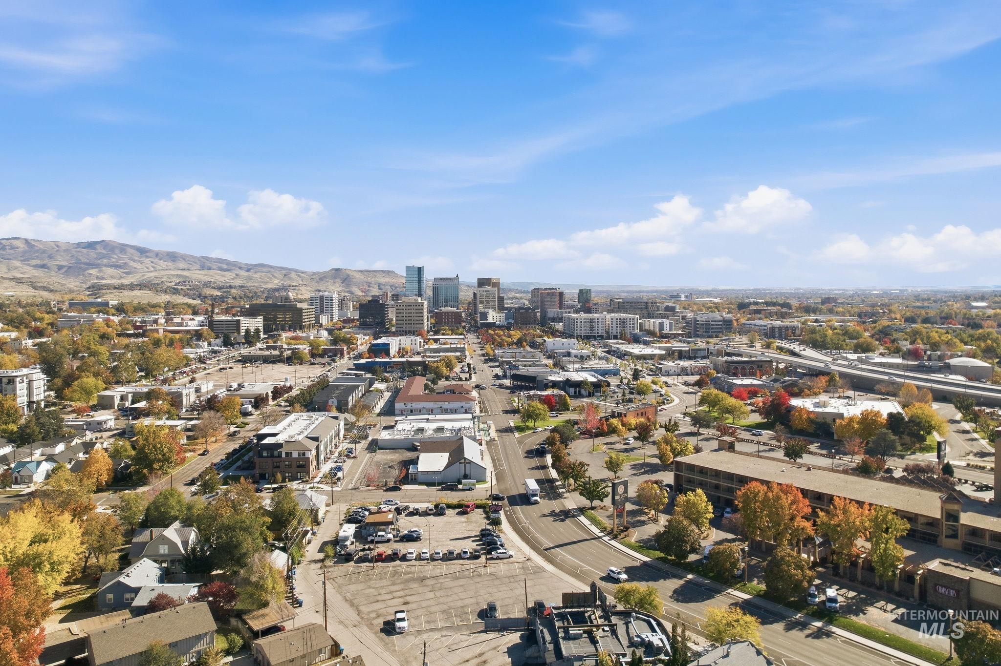 Aerial view of property and surrounding area with nearby urban area and a mountainous background