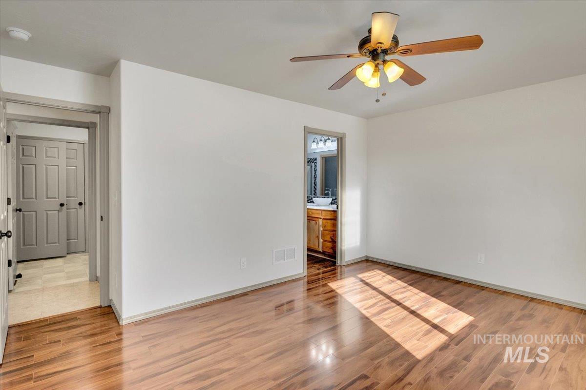 Unfurnished bedroom with light wood-type flooring, ceiling fan, and connected bathroom