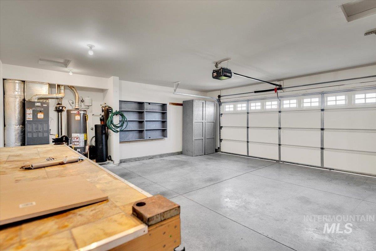 Garage with water heater, a garage door opener, and heating unit