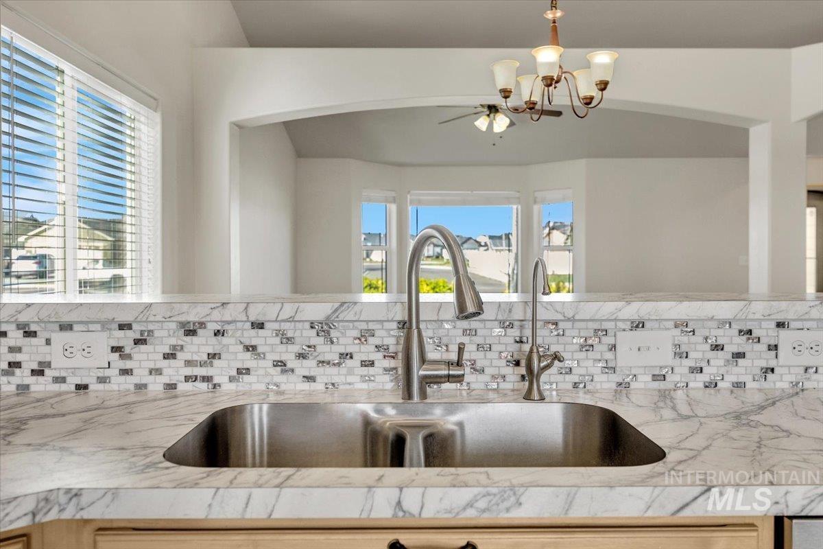 Kitchen view of light stone counters and suspended lighting