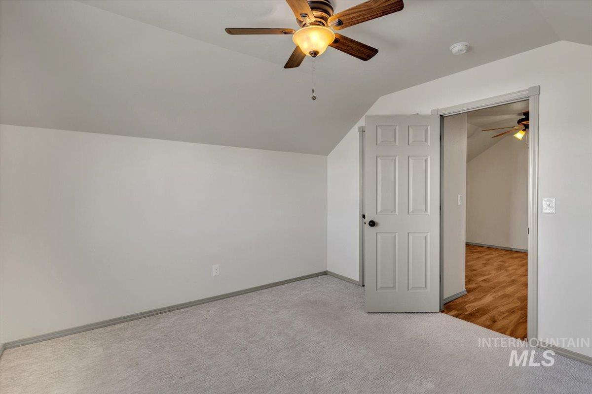 Bedroom featuring a ceiling fan, lofted ceiling, and light carpet