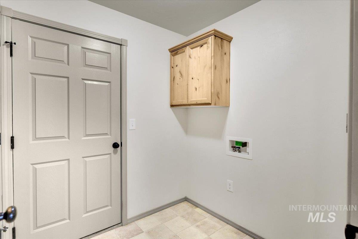 Laundry room featuring light flooring, hookup for a washing machine, and cabinet space
