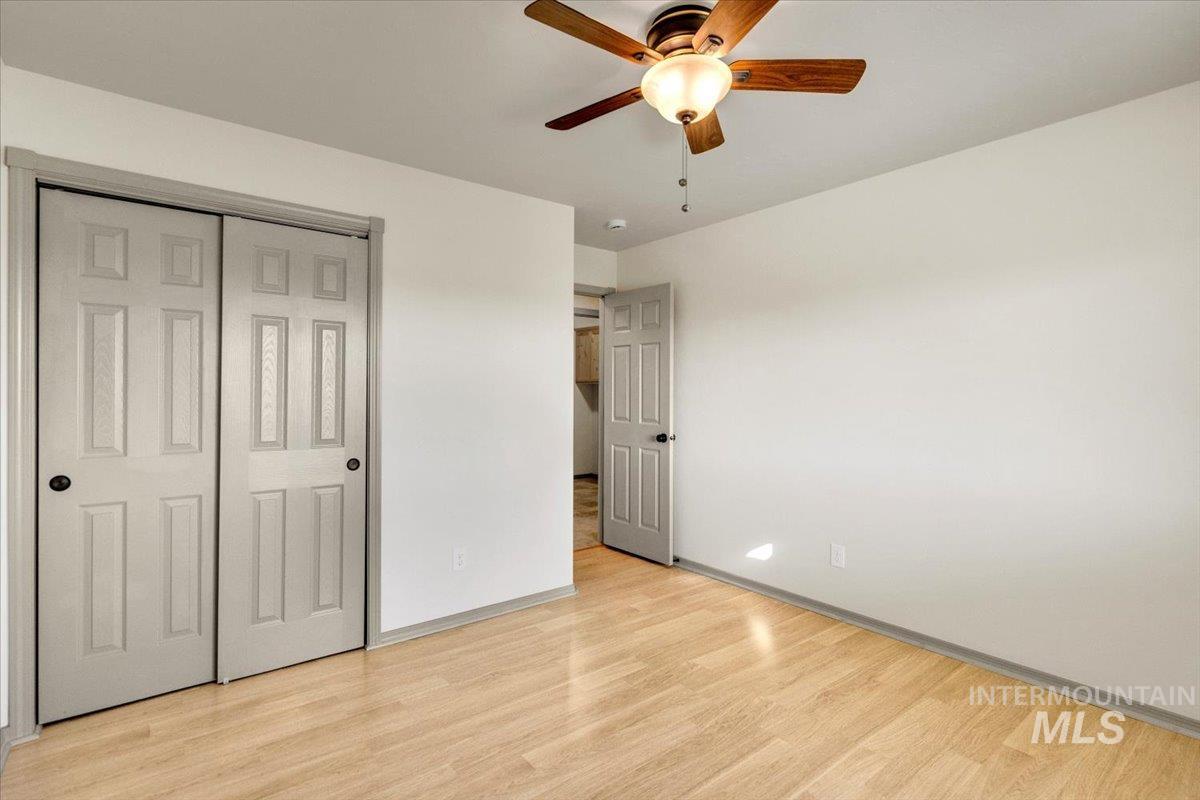 Unfurnished bedroom featuring light wood-type flooring, ceiling fan, and a closet