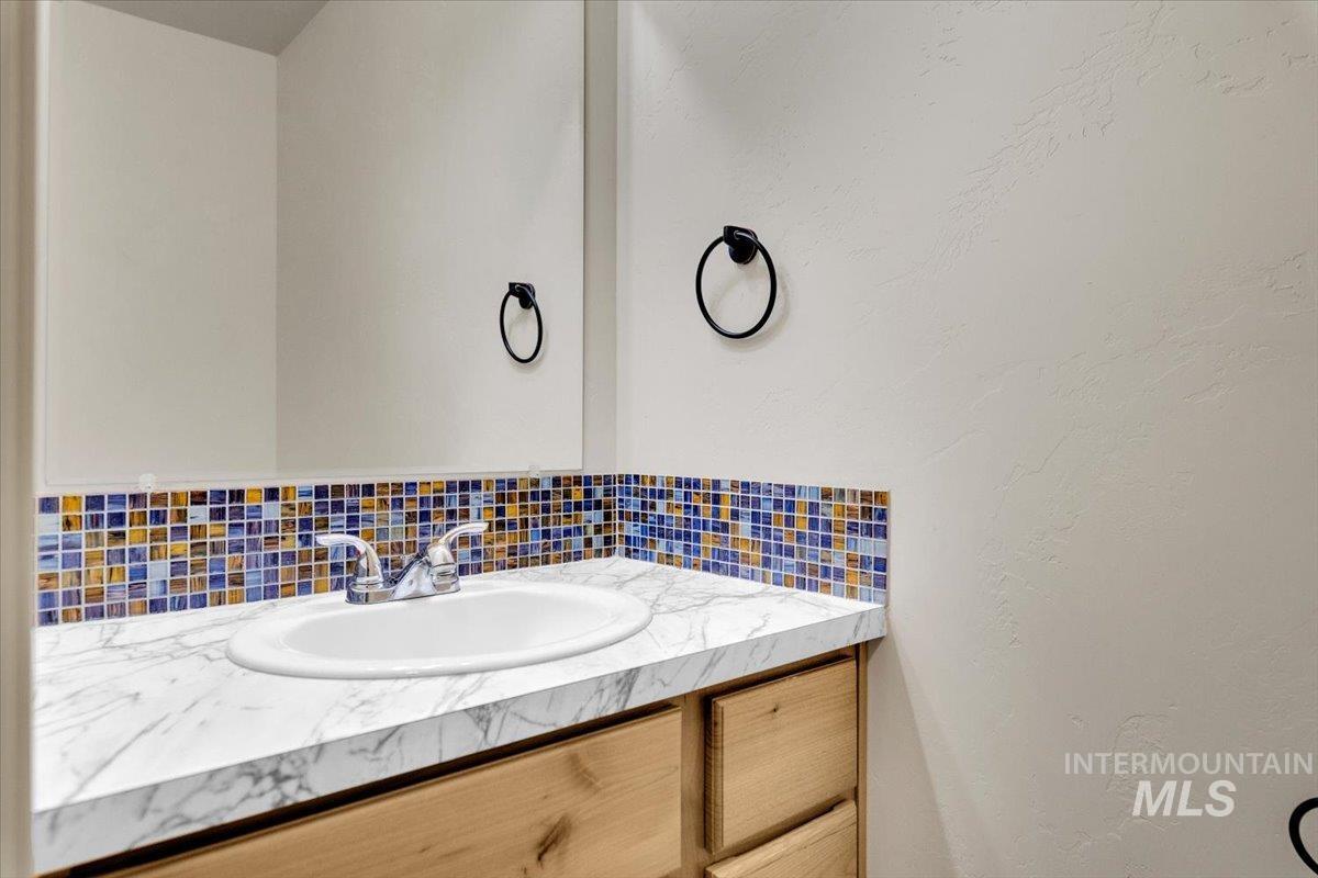 Bathroom featuring vanity, decorative backsplash, and a textured wall