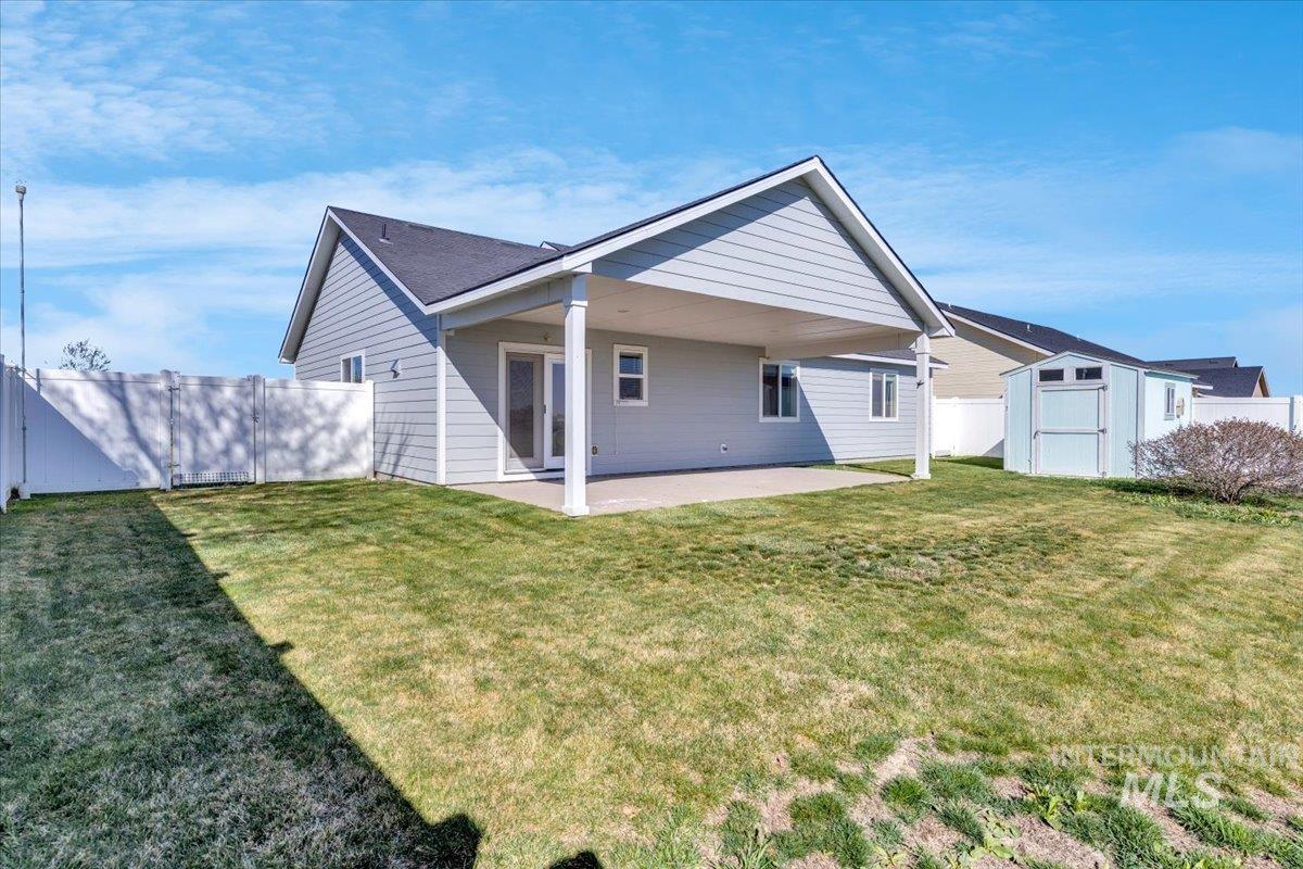 Rear view of house with a patio, a storage shed, and a fenced backyard