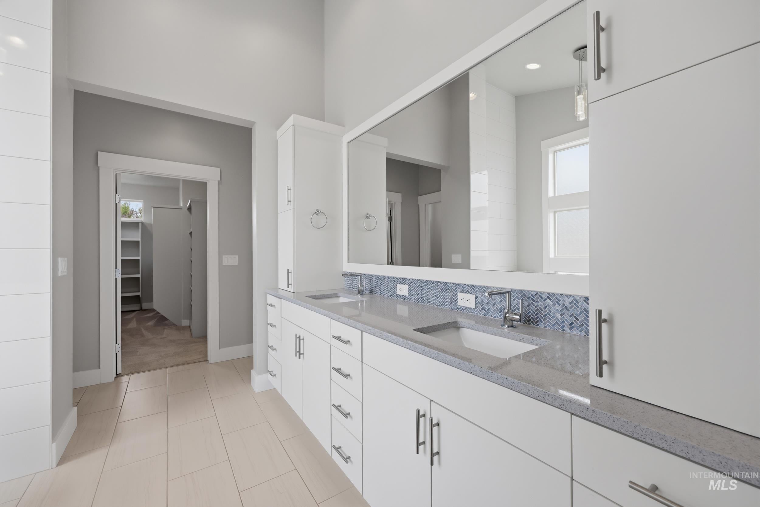 Double vanity with integrated sinks, light-colored countertops, and blue mosaic tile backsplash