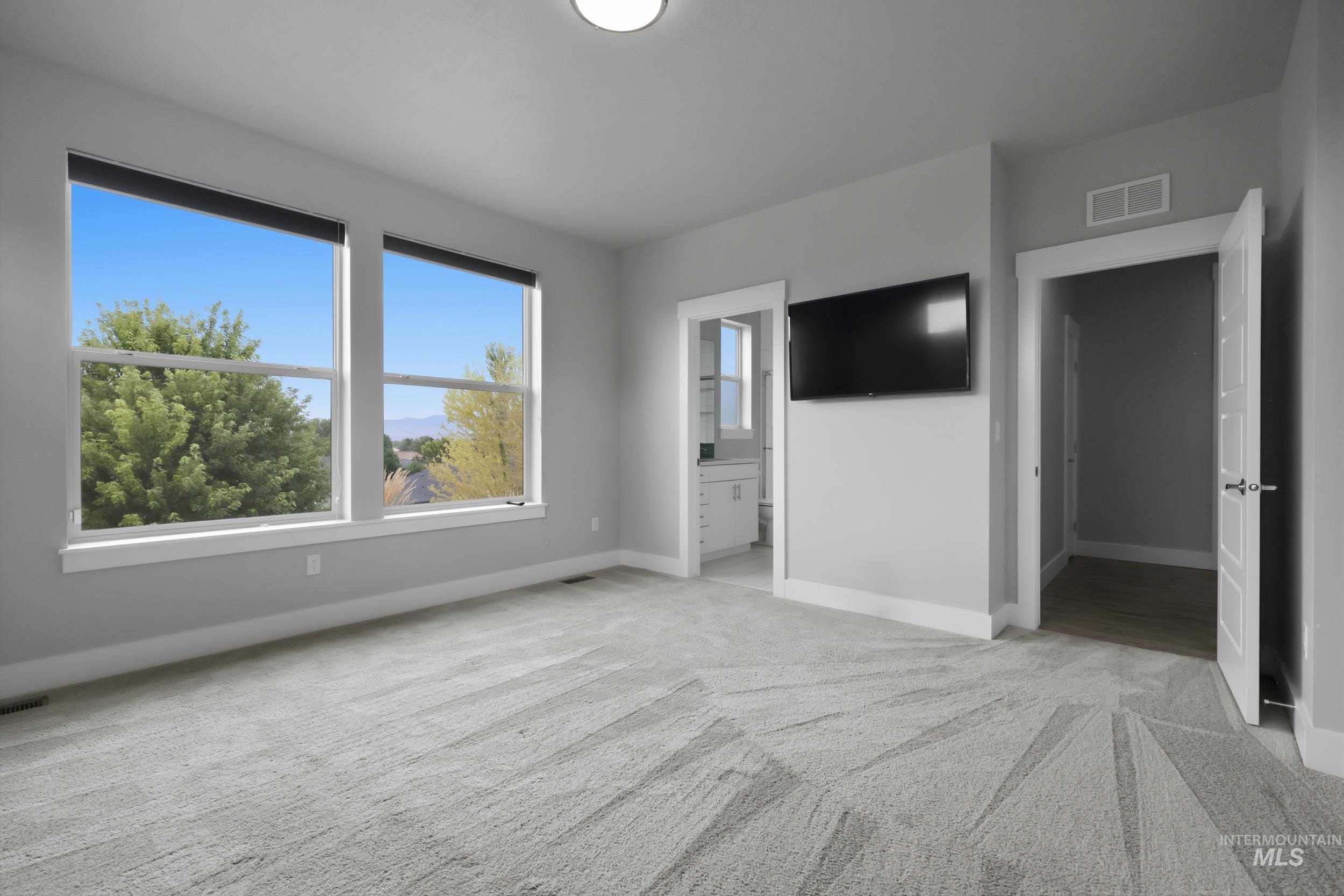 Spacious room featuring multiple windows, patterned carpeting, and painted walls