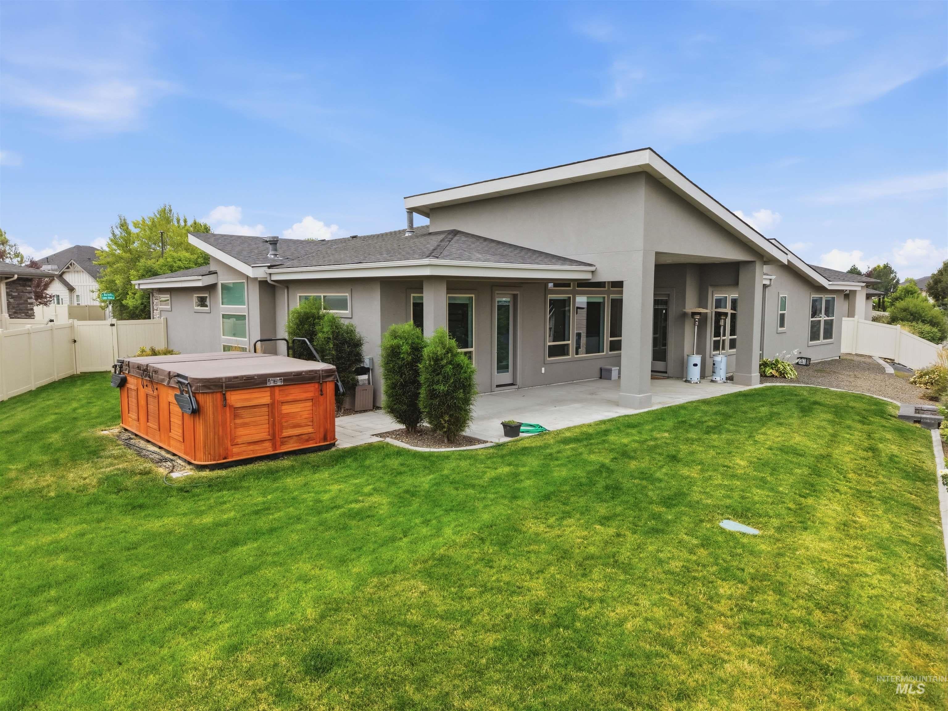 Expansive backyard featuring a built-in spa with a wood-panel surround, a concrete patio, and a sloped lawn