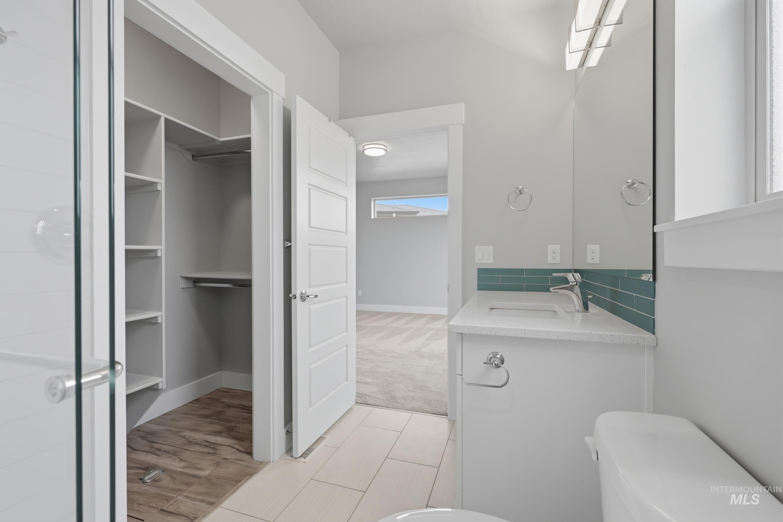 Bathroom featuring a single vanity with an integrated sink, polished chrome faucet, and teal subway tile backsplash