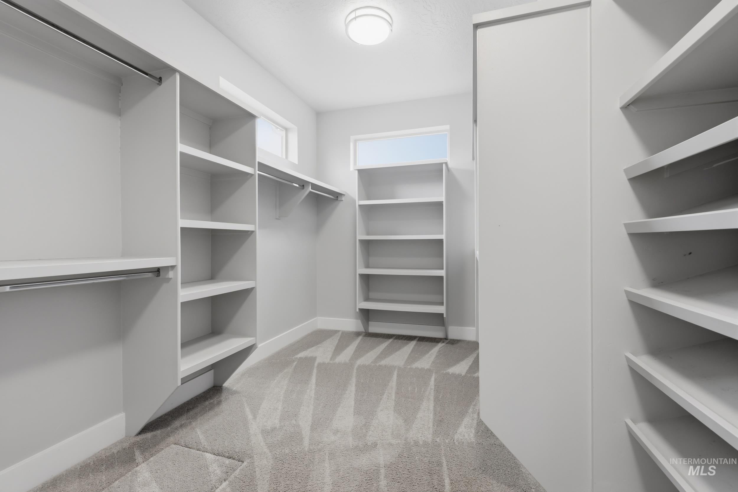 Walk-in closet featuring built-in shelving, multiple hanging rods, durable carpeting, and recessed ceiling lighting