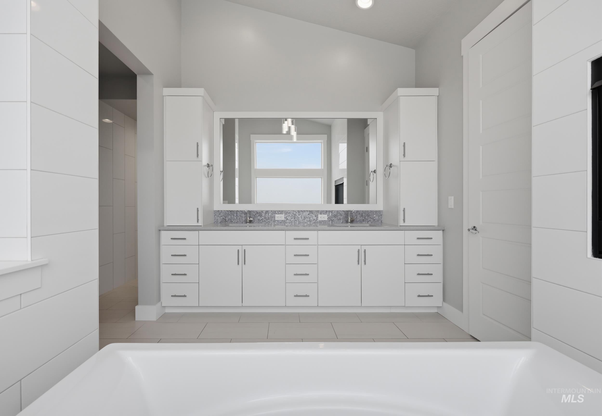 White dual vanity with integrated sinks, light-colored stone countertop, and extensive storage cabinetry