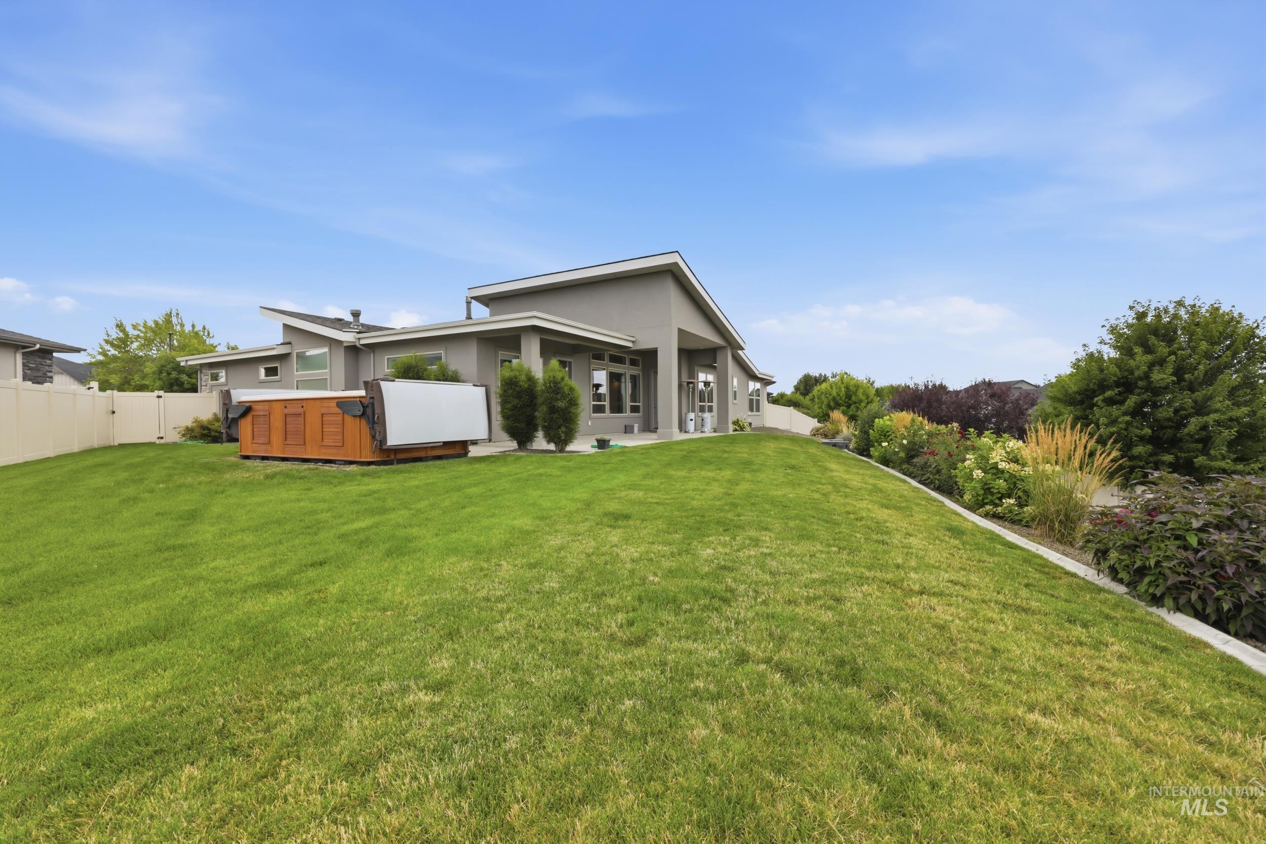 Spacious backyard featuring a sloped lawn and extensive landscaping