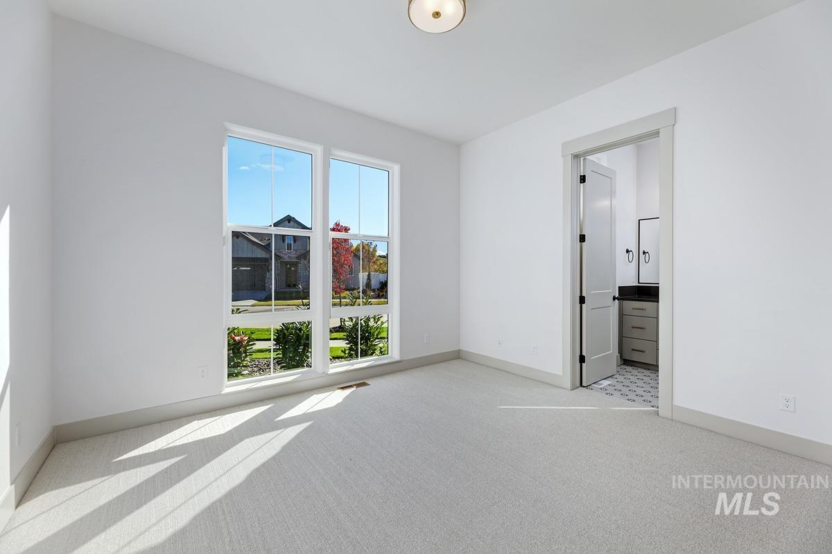 Unfurnished bedroom featuring light carpet and ensuite bathroom