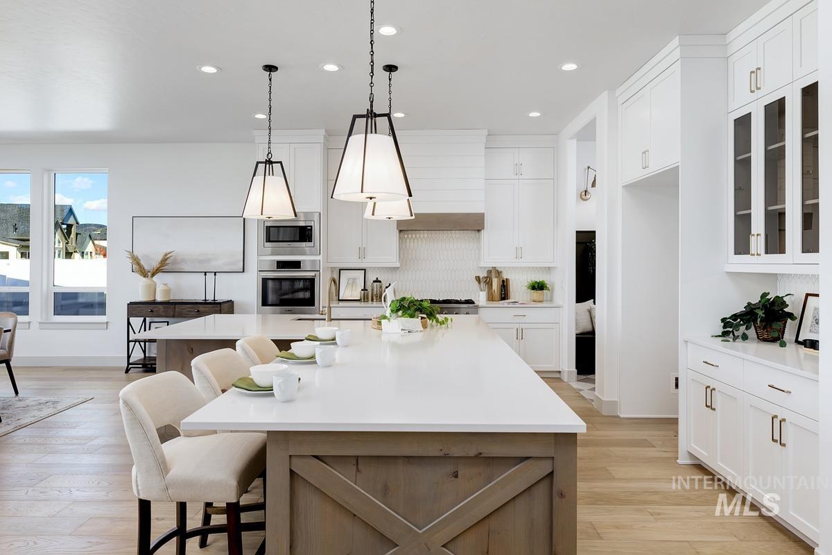 Kitchen with light wood-style flooring, an island with sink, white cabinetry, a breakfast bar, and recessed lighting
