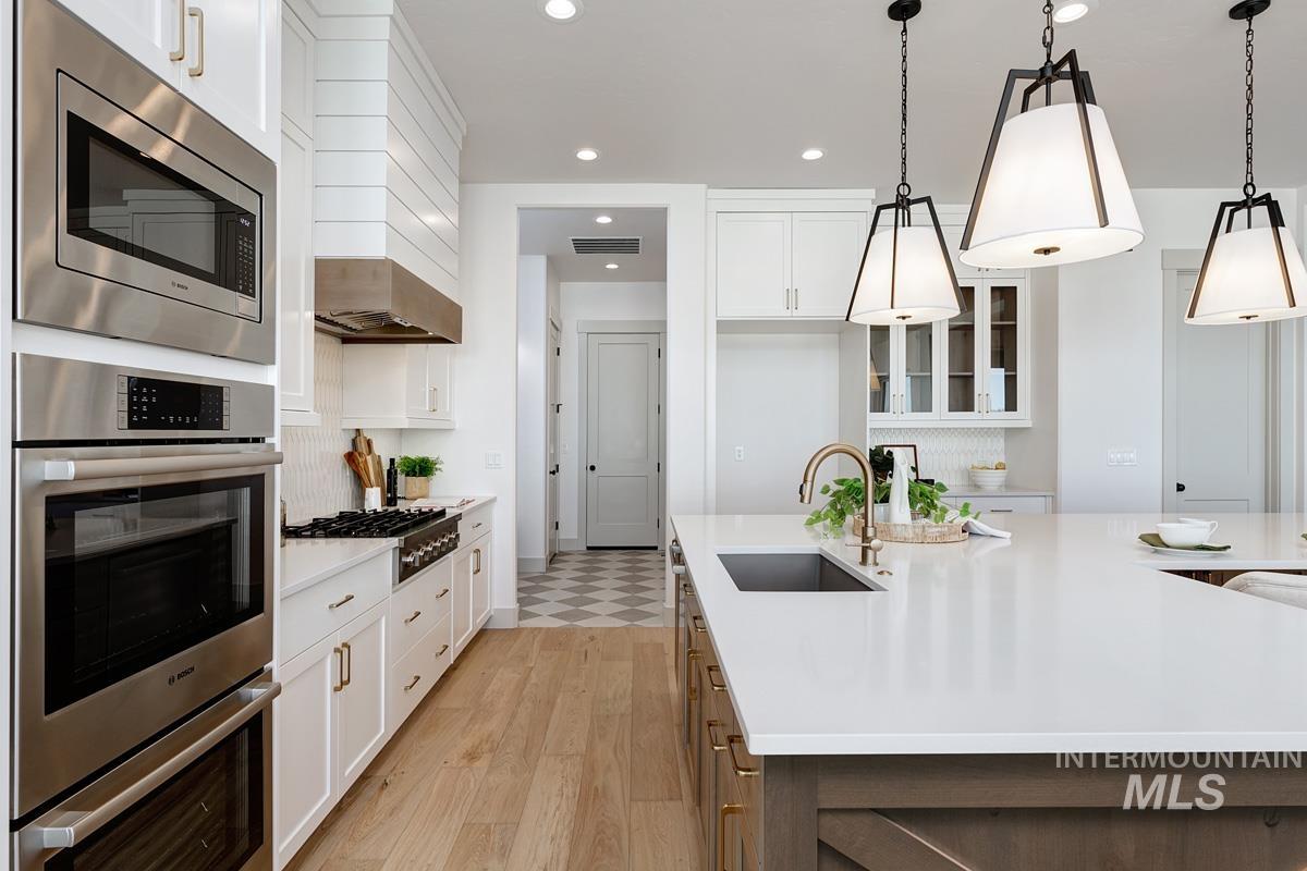Kitchen with recessed lighting, white cabinets, stainless steel appliances, and light wood finished floors