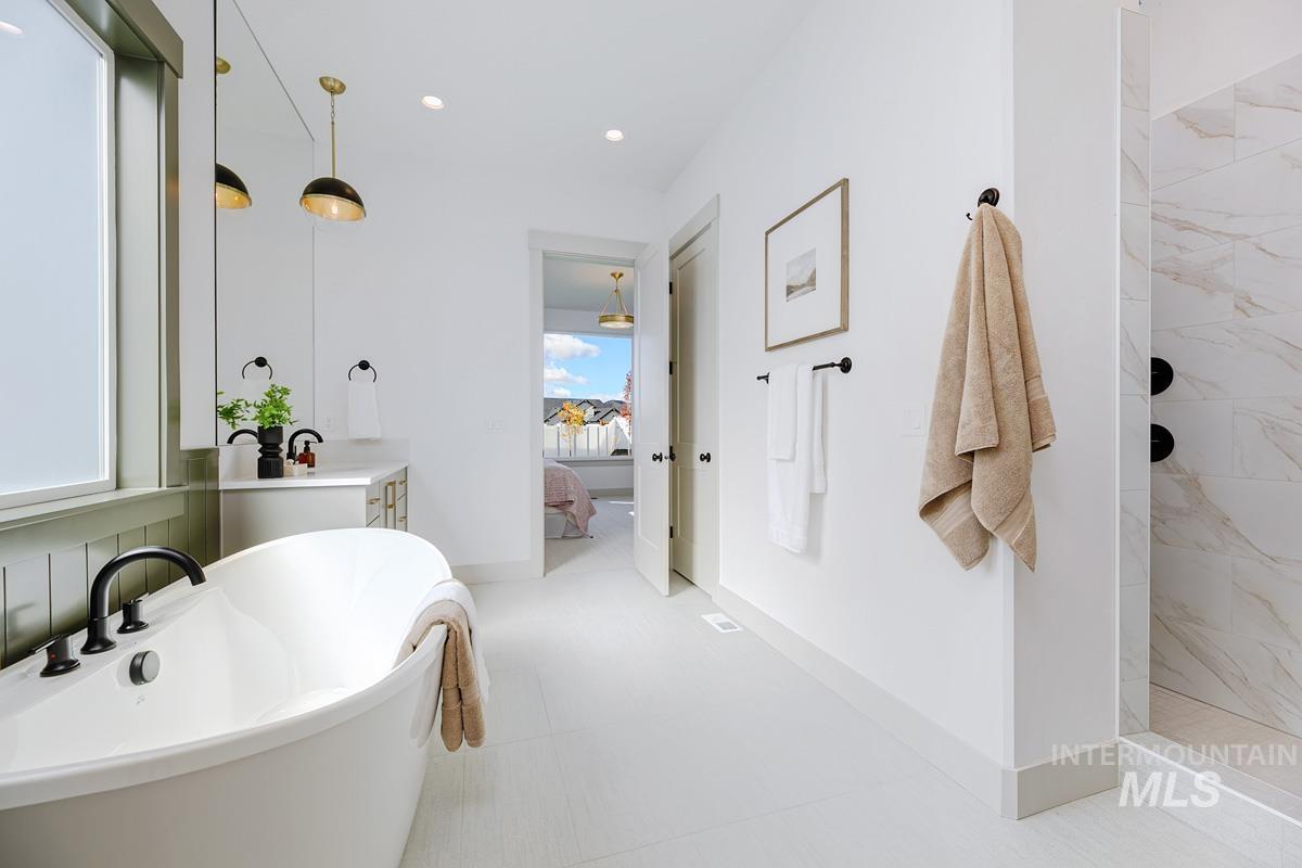 Bathroom featuring ensuite bathroom, a freestanding tub, vanity, recessed lighting, and a walk in shower