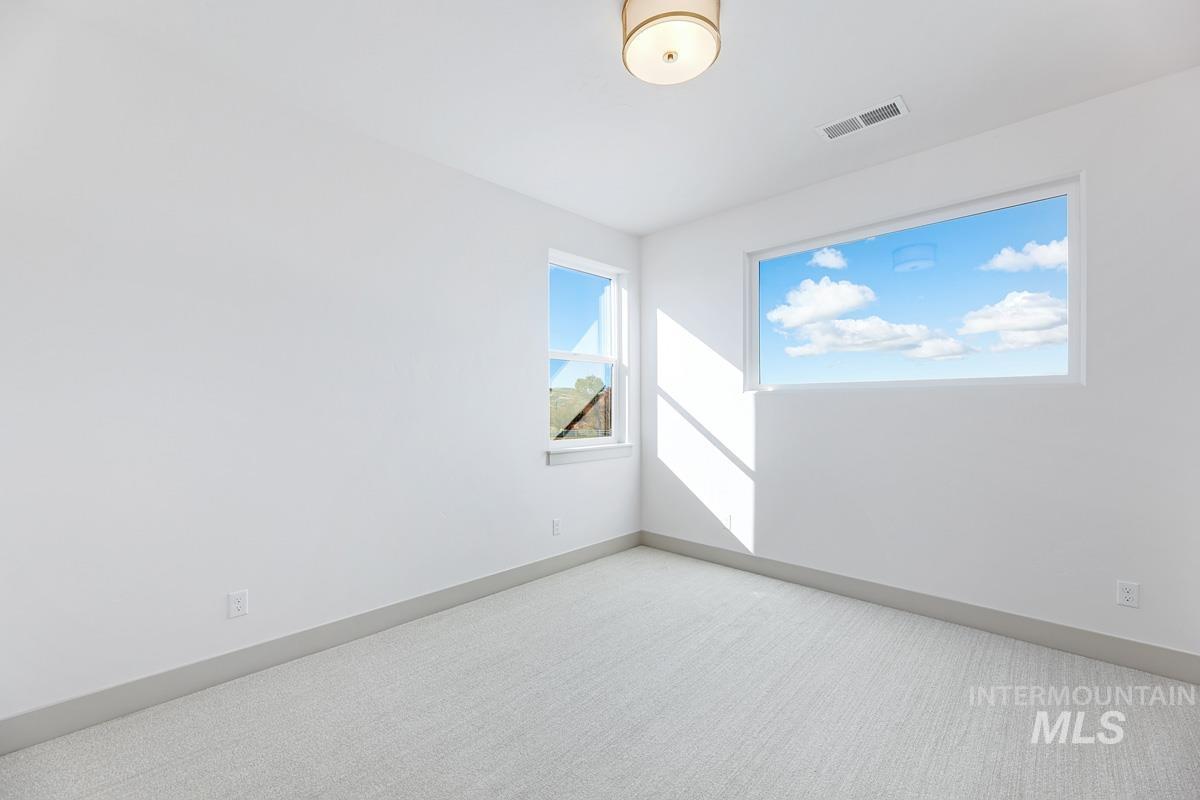 Carpeted spare room featuring baseboards